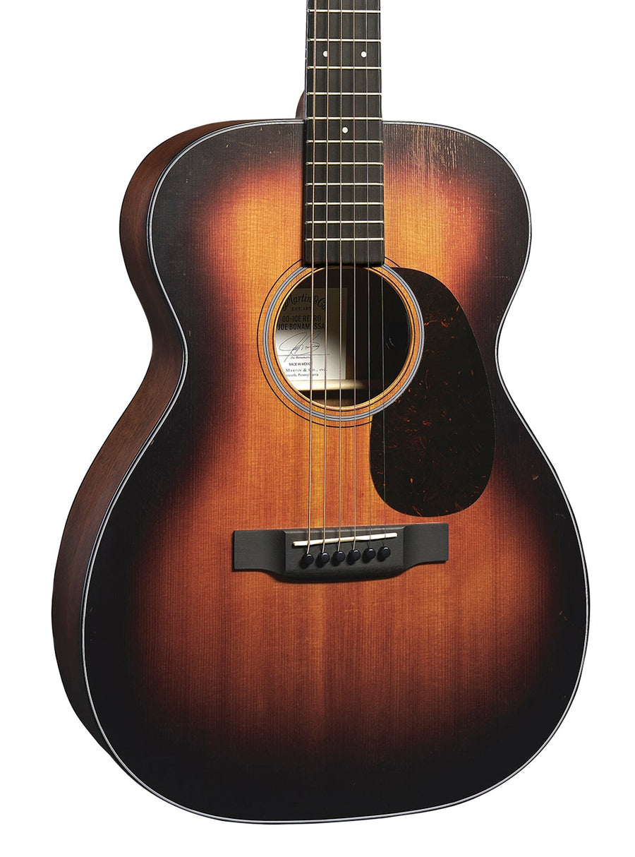 Guitare acoustique forme parlor, finition sunburst dégradée du noir au brun, six cordes, pickguard sombre près de la rosace.