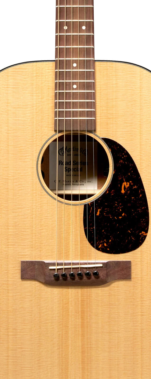 Light wood acoustic guitar with six strings, a dark wooden bridge, circular sound hole, and a large tortoiseshell-patterned pickguard.