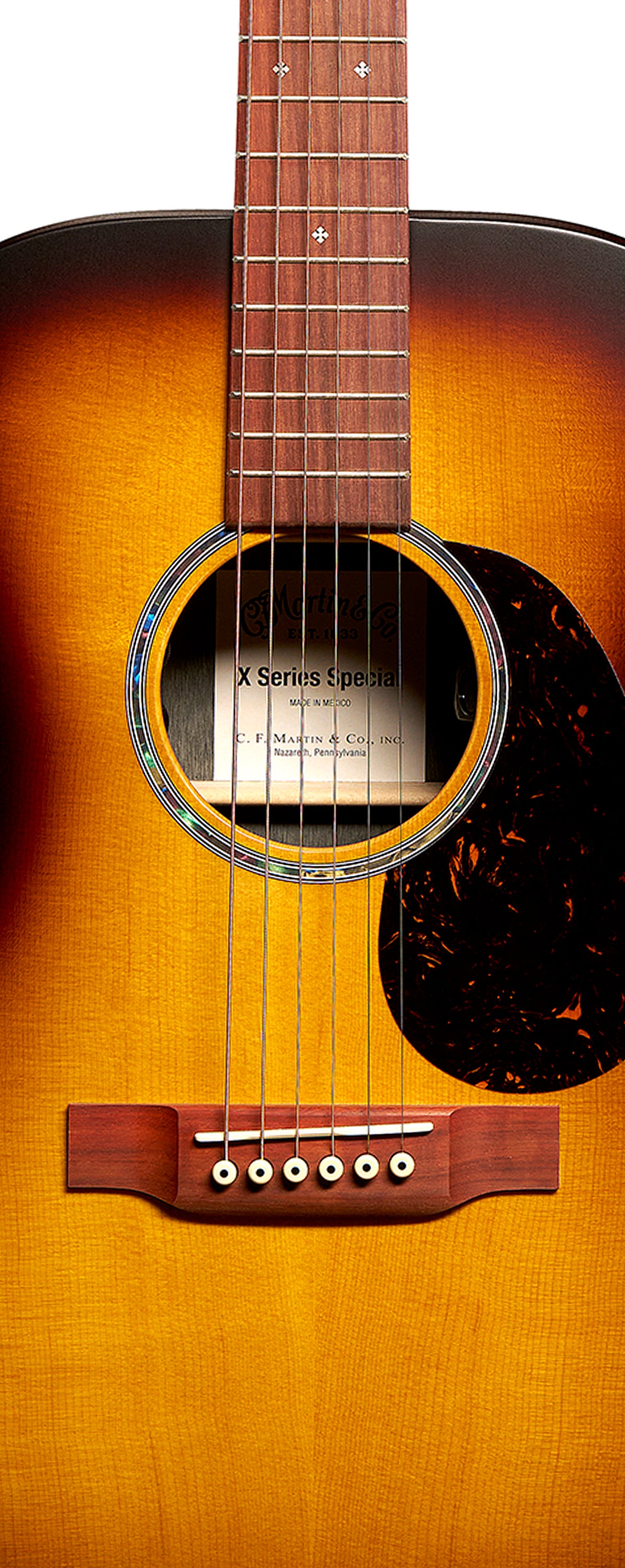 Guitare acoustique à six cordes, finition dégradée du brun au jaune, avec rosace et pickguard foncé marbré sur la droite des cordes.