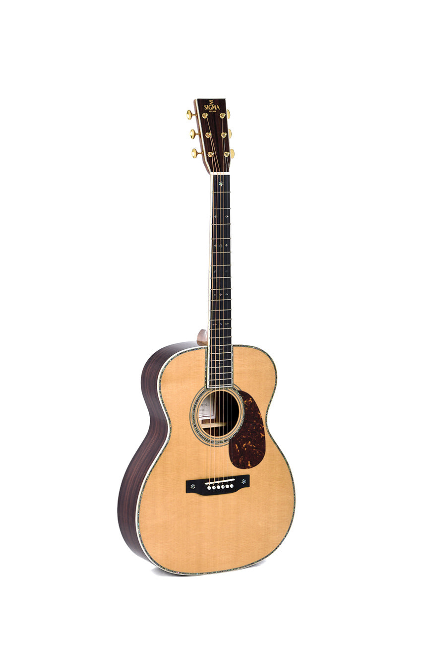 Acoustic guitar with a light wood top, dark sides and back, six strings, gold tuning pegs, tortoiseshell pickguard, and decorative inlays on the neck.