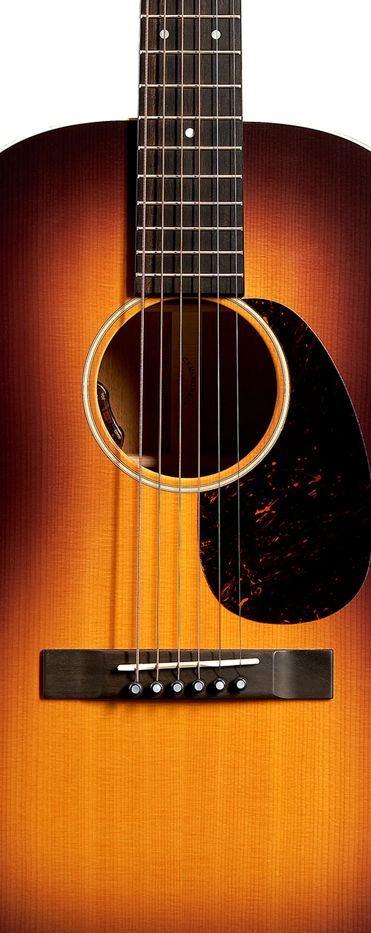 Guitare acoustique avec table en bois dégradé marron et orange, six cordes, rosace ronde et pickguard noir marbré à droite des cordes.