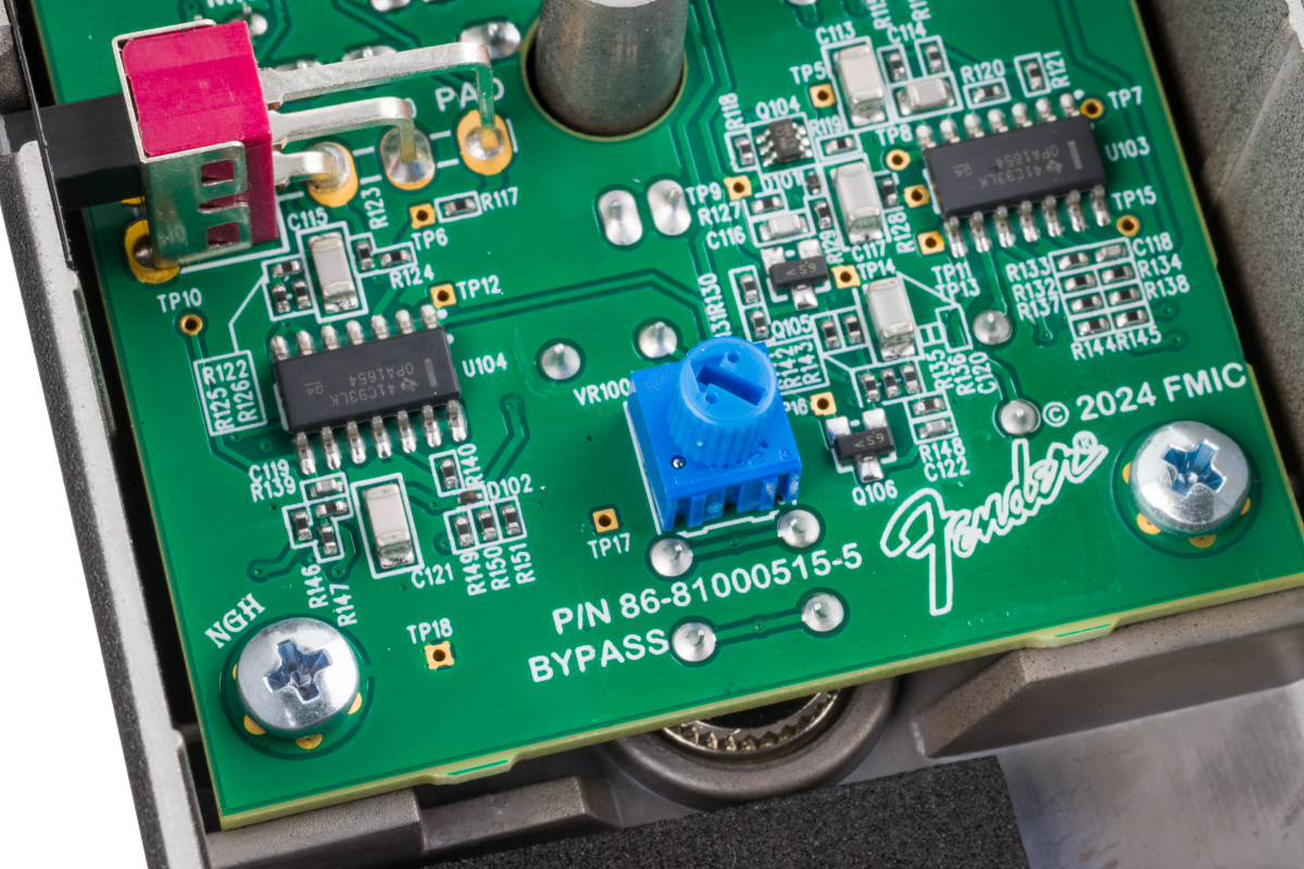 Close-up of a Fender FX pedal circuit board showing microchips, a blue potentiometer, a red switch, and mounting screws.