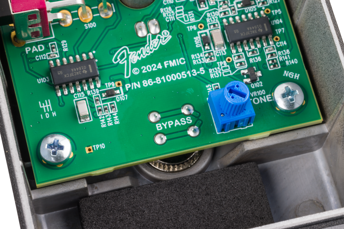 Close-up of a Fender FX pedal circuit board showing electronic components, labeled connections, a blue knob, and the word "BYPASS" printed near the center.