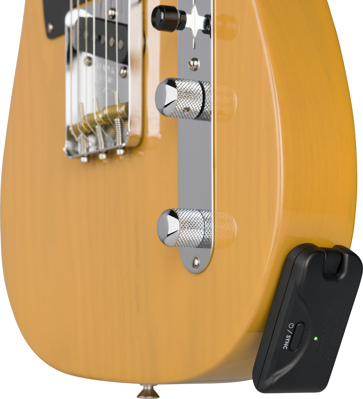 A wireless guitar transmitter accessory plugged into the output jack of a light wood electric guitar, green indicator light on.