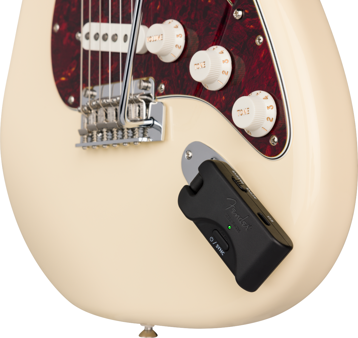 A wireless guitar transmitter is plugged into the input jack of a cream electric guitar near its volume and tone knobs.
