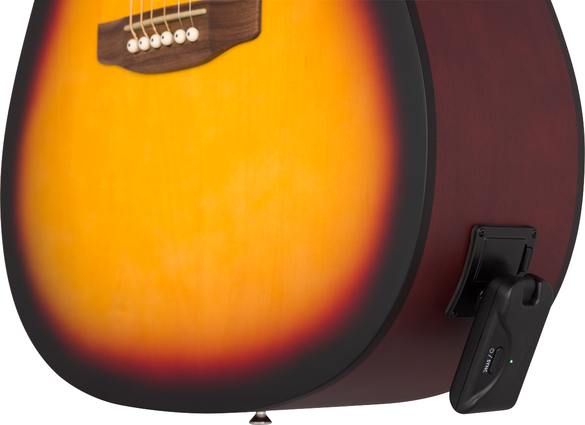 A wireless guitar transmitter is plugged into the side of a sunburst acoustic guitar body near the bridge.