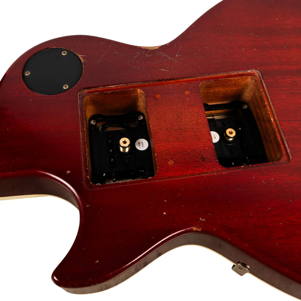 Back of a red electric guitar with a large rectangular electronics cavity open, showing internal battery compartments, and some visible scratches.