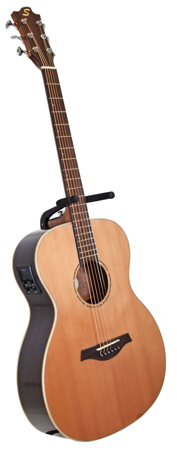 Six-string acoustic guitar with a natural wood top, dark sides, and electronic controls on the side panel, resting on a wall hanger.