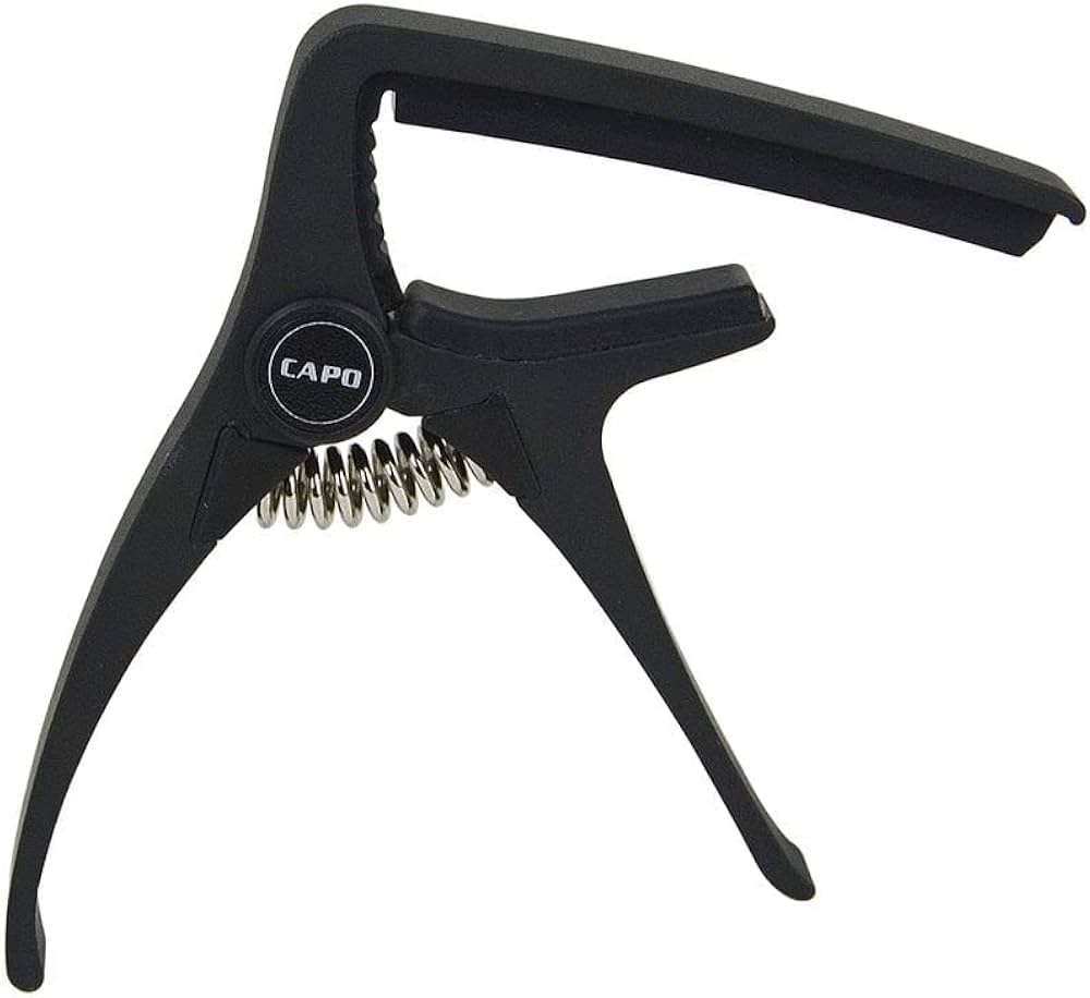 Black guitar capo with a spring-loaded clamp design and the word "CAPO" printed on a circular section near the hinge.
