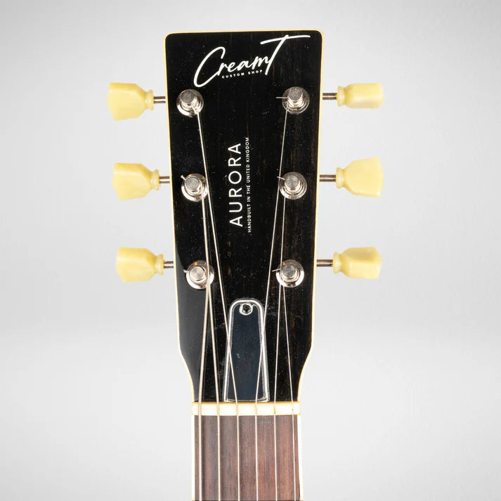 Electric guitar headstock with six tuning pegs, yellow knobs, and “CreamT Custom Shop Aurora” branding on a black background.
