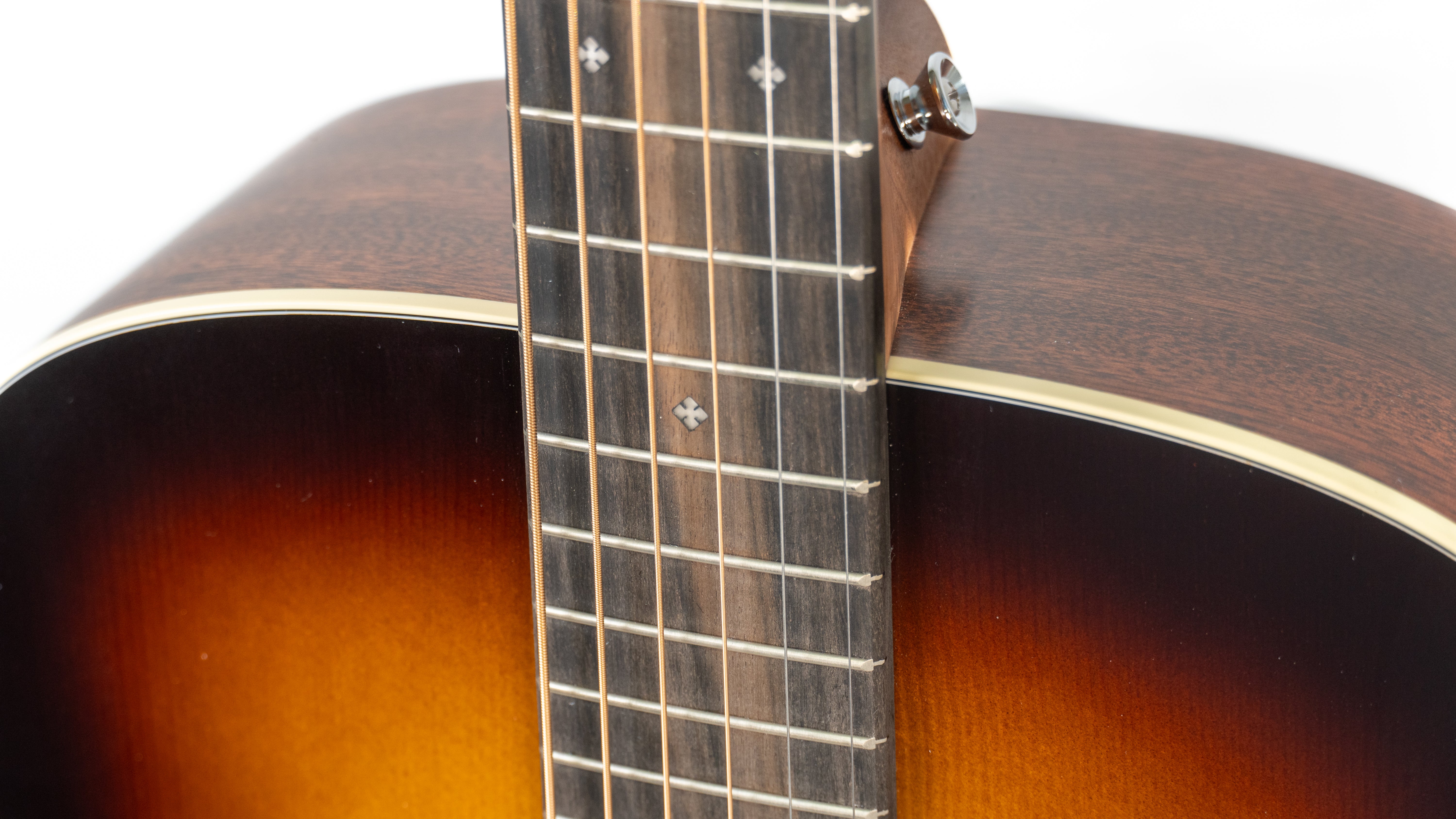 Close-up of an acoustic guitar showing a sunburst body, a dark wood neck with diamond-shaped inlays, and cream binding along the edge.