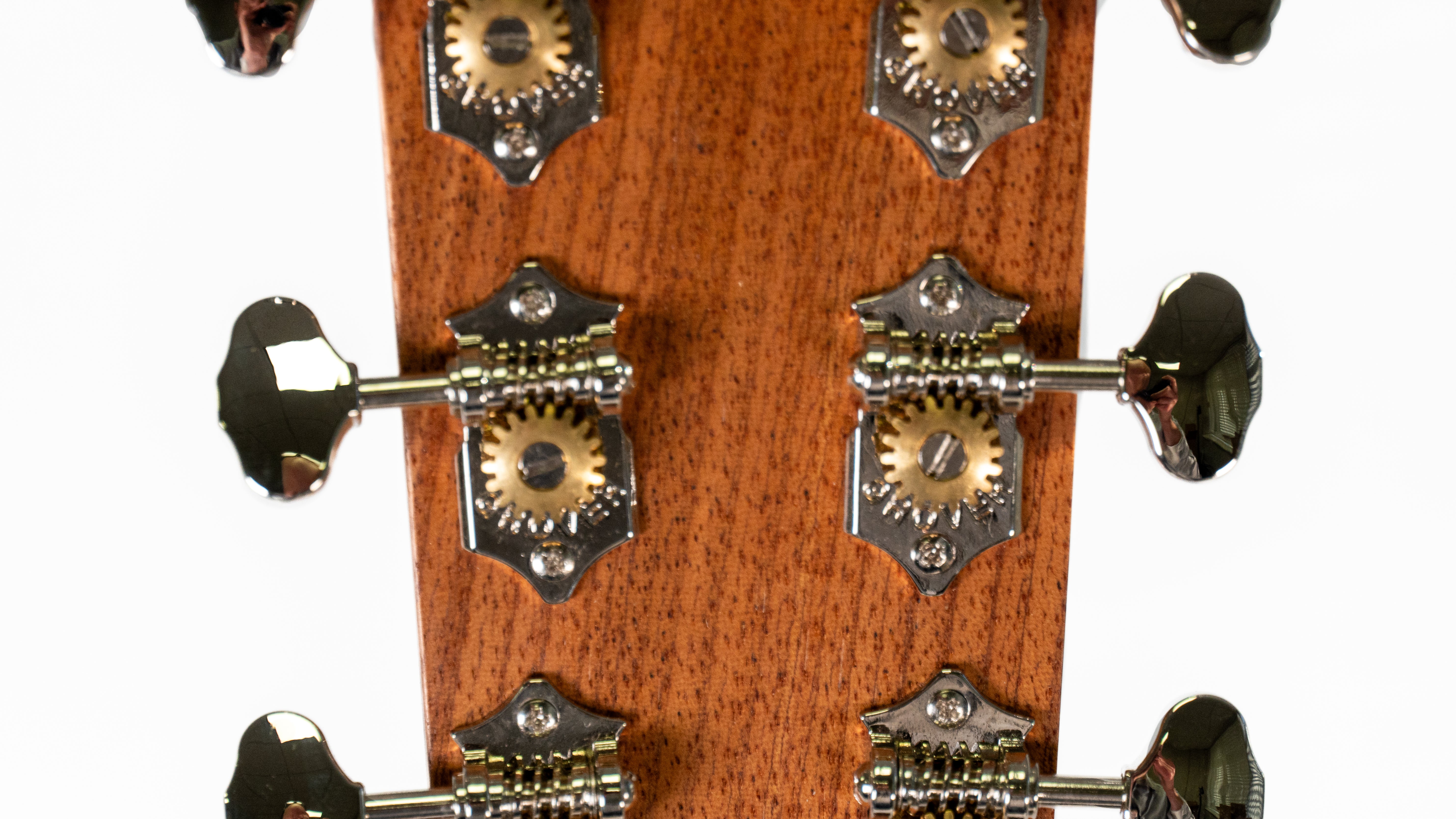 Six shiny metal tuning pegs and gears mounted on a wooden acoustic guitar headstock, used to adjust string tension.