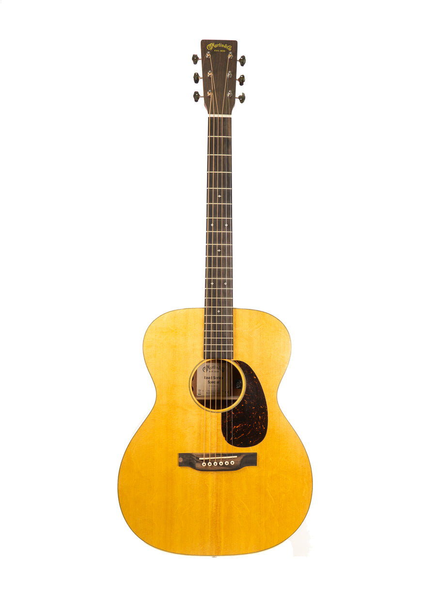 Wood-finished acoustic guitar with six strings, dark fingerboard, rounded body, and a dark teardrop-shaped pickguard next to the sound hole.