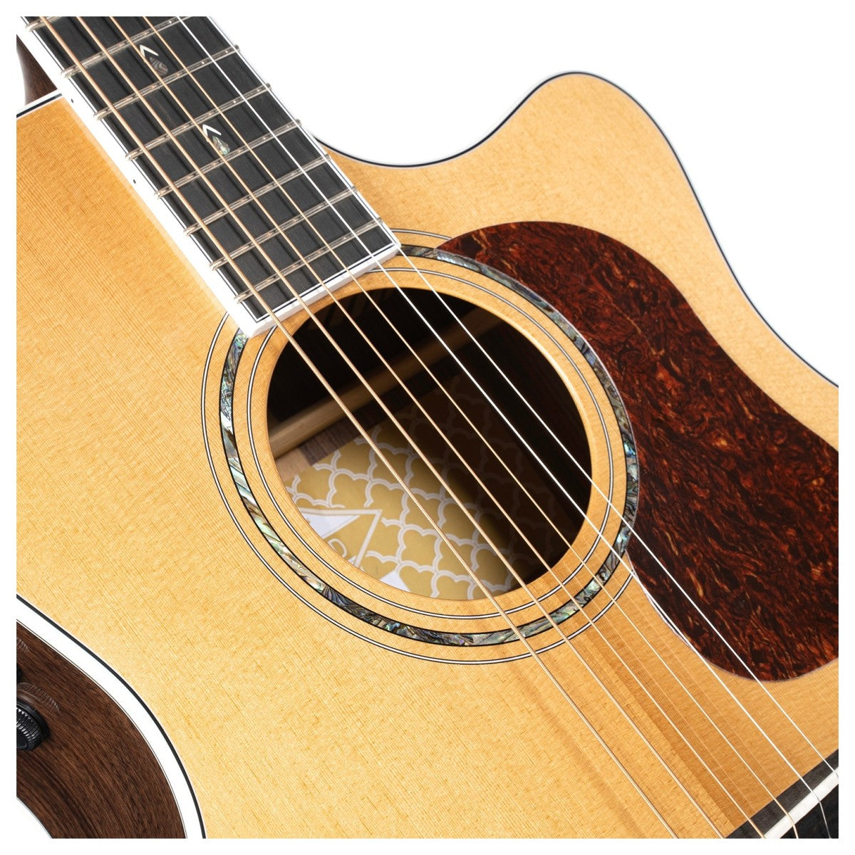 Close-up of an acoustic guitar body showing six strings, a decorative sound hole, and a dark, textured pickguard on a light wood finish.