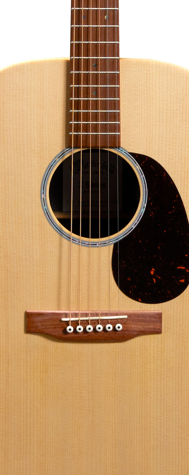 Light wood acoustic guitar body with six steel strings, dark wooden fretboard, round soundhole, black pickguard, and six bridge pins.