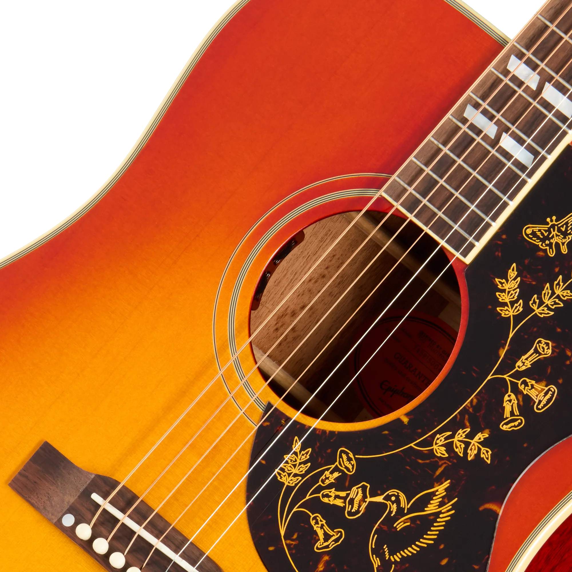 Guitare acoustique avec finition sunburst orange à jaune, pickguard noir décoré de motifs floraux dorés et oiseau gravé près de la rosace.