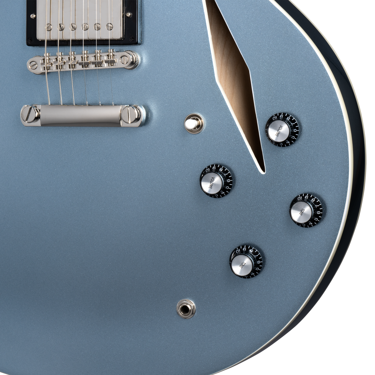 Metallic blue electric guitar body with four black control knobs, silver tailpiece, and a sharp f-shaped sound hole on the upper right.