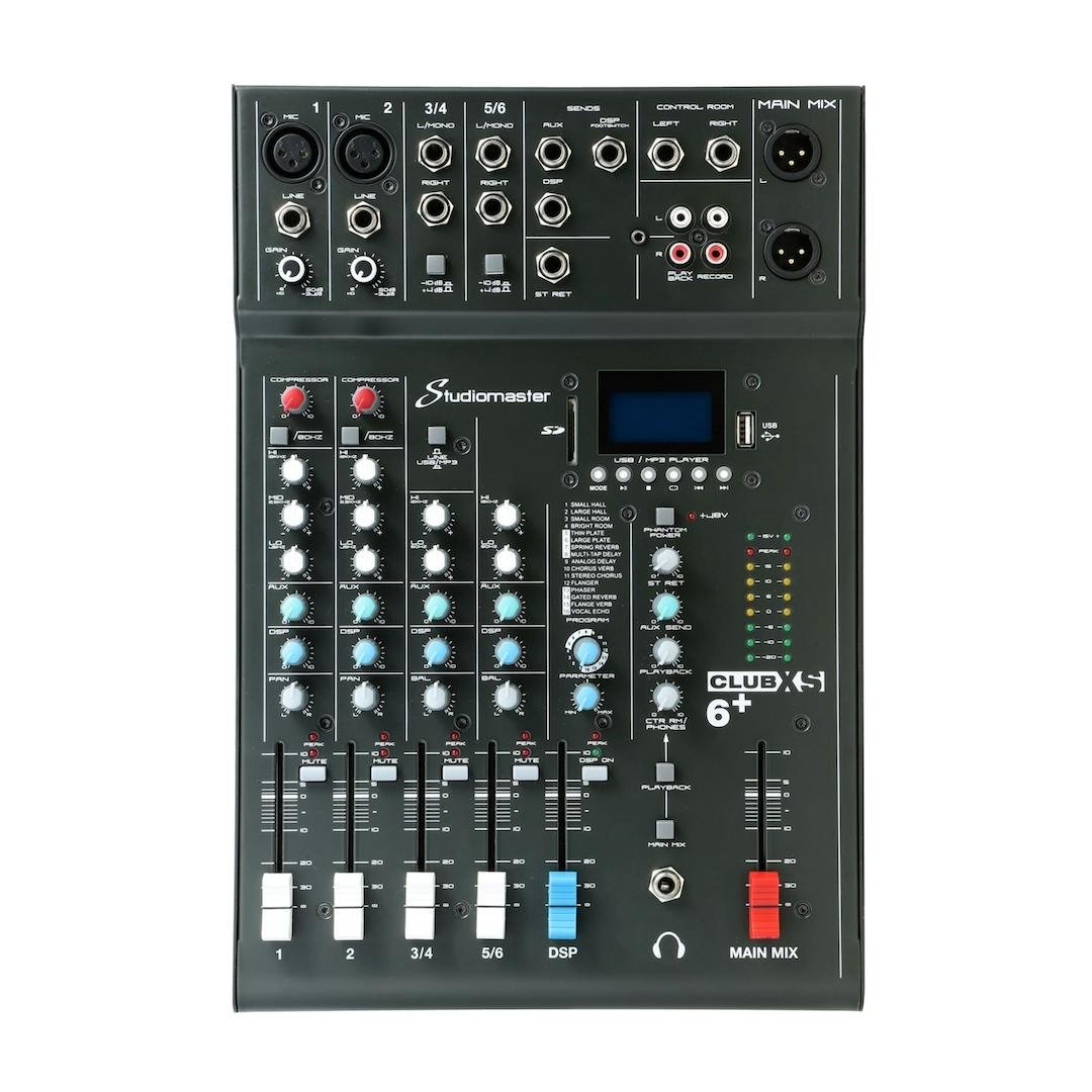 Studiomaster Club XS 6+ audio mixer with multiple knobs, sliders, input/output ports, a digital display, and USB/MP3 player controls.