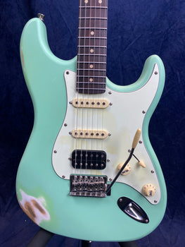 Seafoam green electric guitar with a white pickguard, visible wear near the edge, three pickups, and cream-colored knobs and pickup covers.