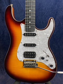 Sunburst electric guitar with a white pearloid pickguard, three pickups, chrome controls, and a tremolo arm, set against a dark background.