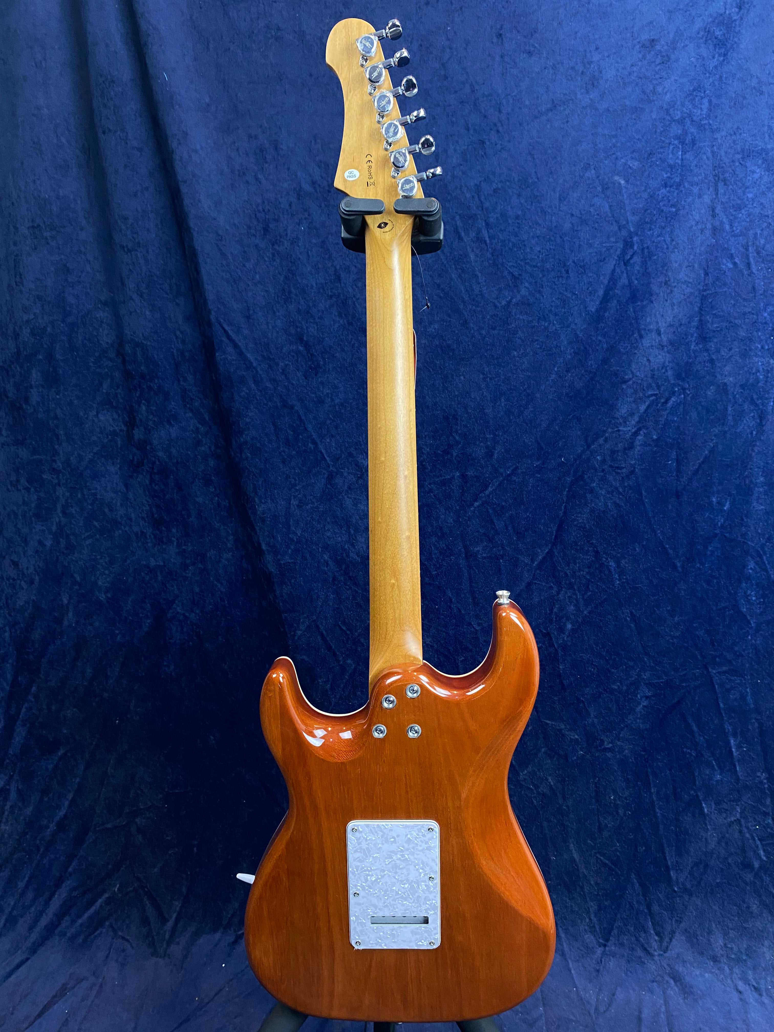 Electric guitar shown from the back, with a glossy brown body, light wood neck, and chrome tuning pegs against a dark blue background.
