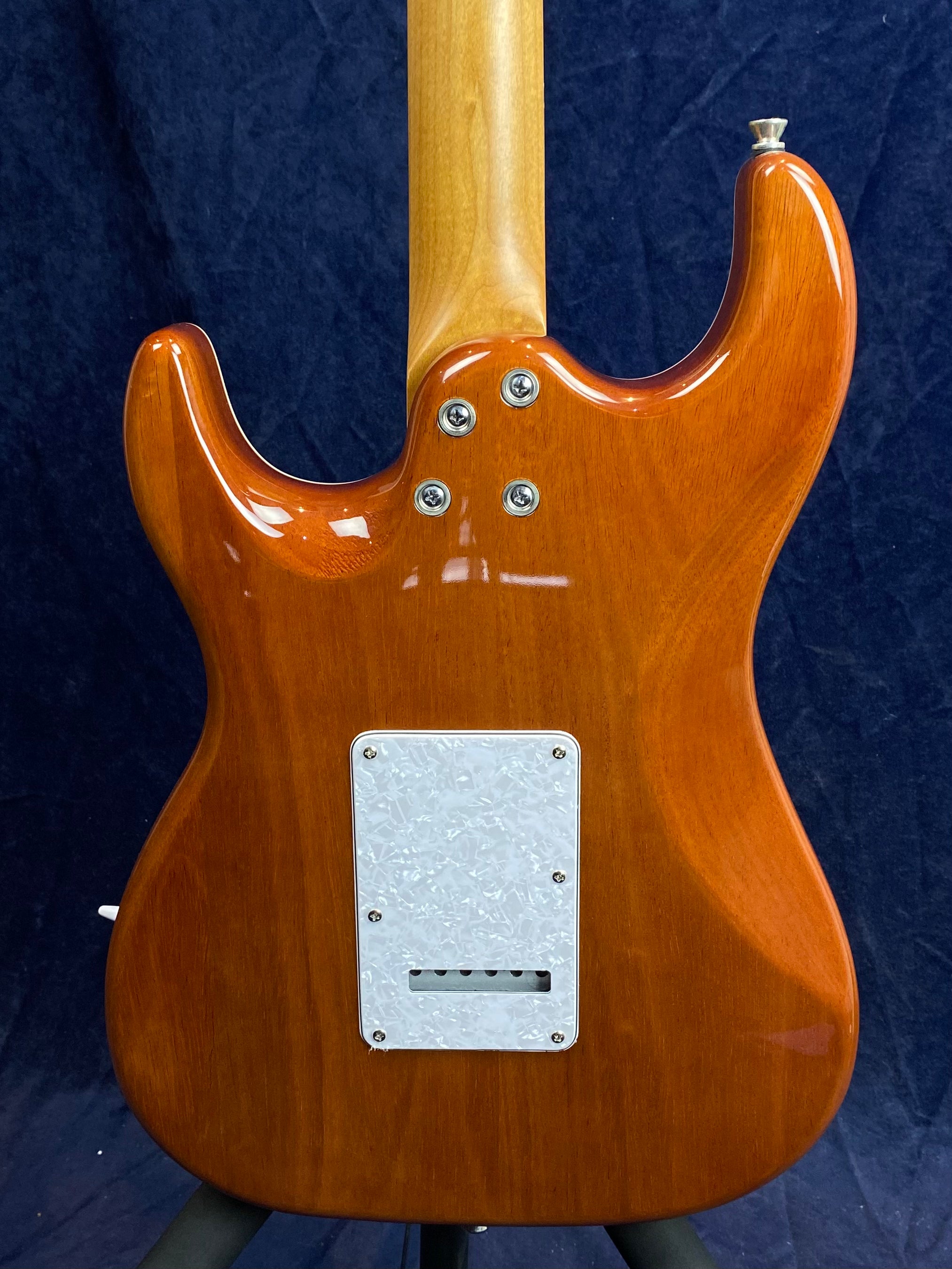Glossy brown electric guitar back, four neck screws, white marbled rectangular plate covering the tremolo cavity near the bottom, neck is natural wood.