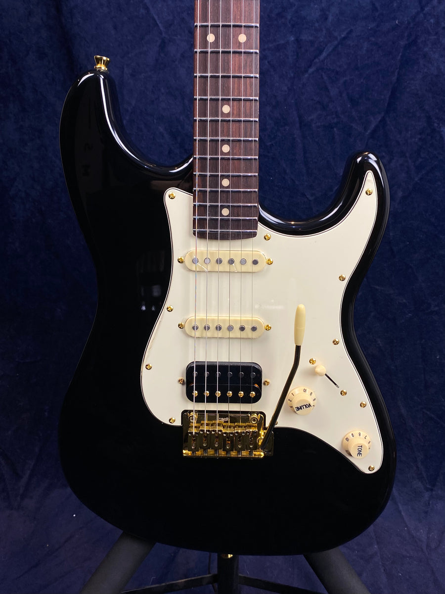 Jet electric guitar with a glossy black body, white pickguard, gold hardware, three pickups, and two cream control knobs.