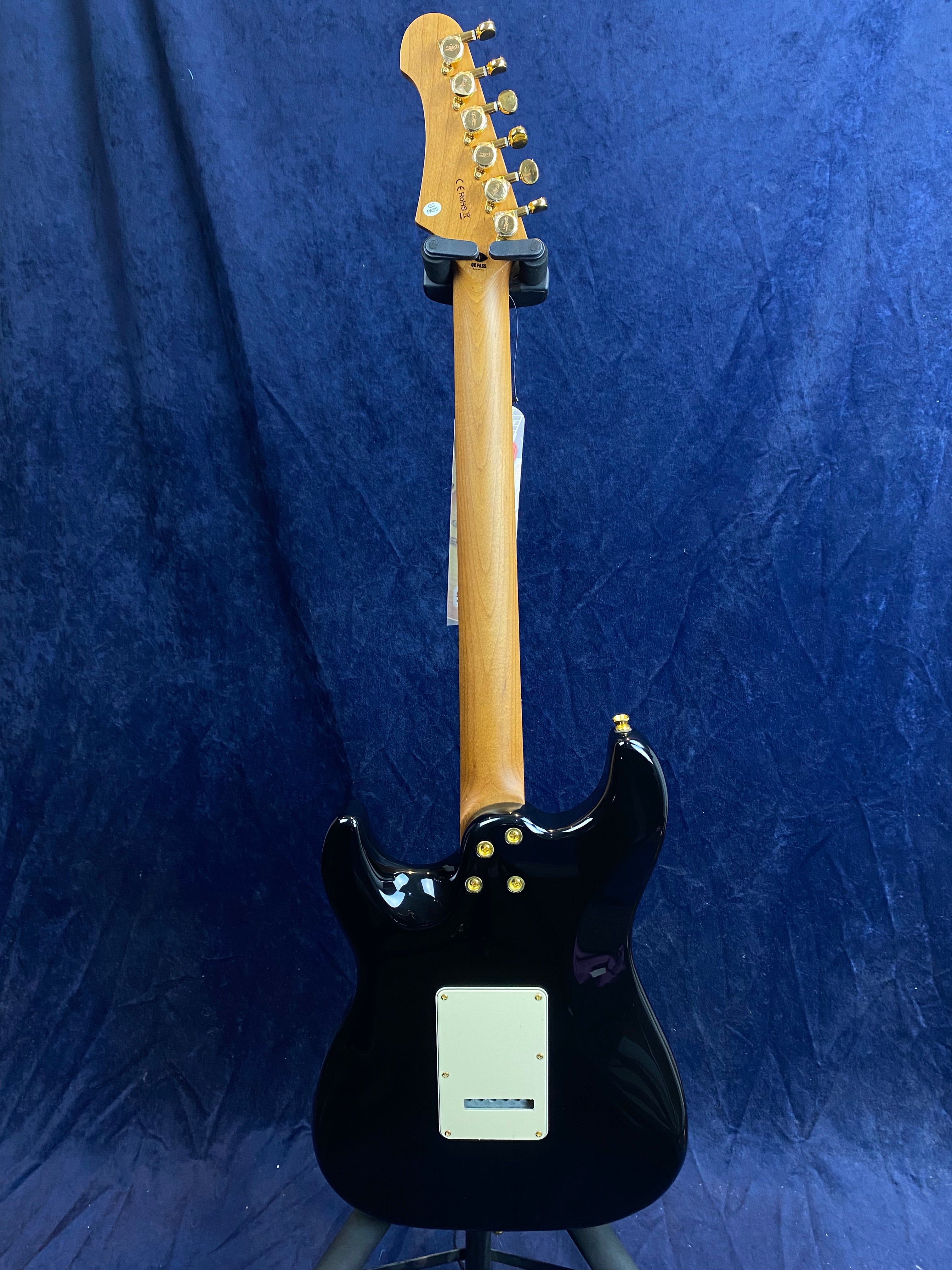Jet Guitars electric guitar shown from the back, black body, natural wood neck, six gold tuning pegs, and a rectangular white plate on the body.