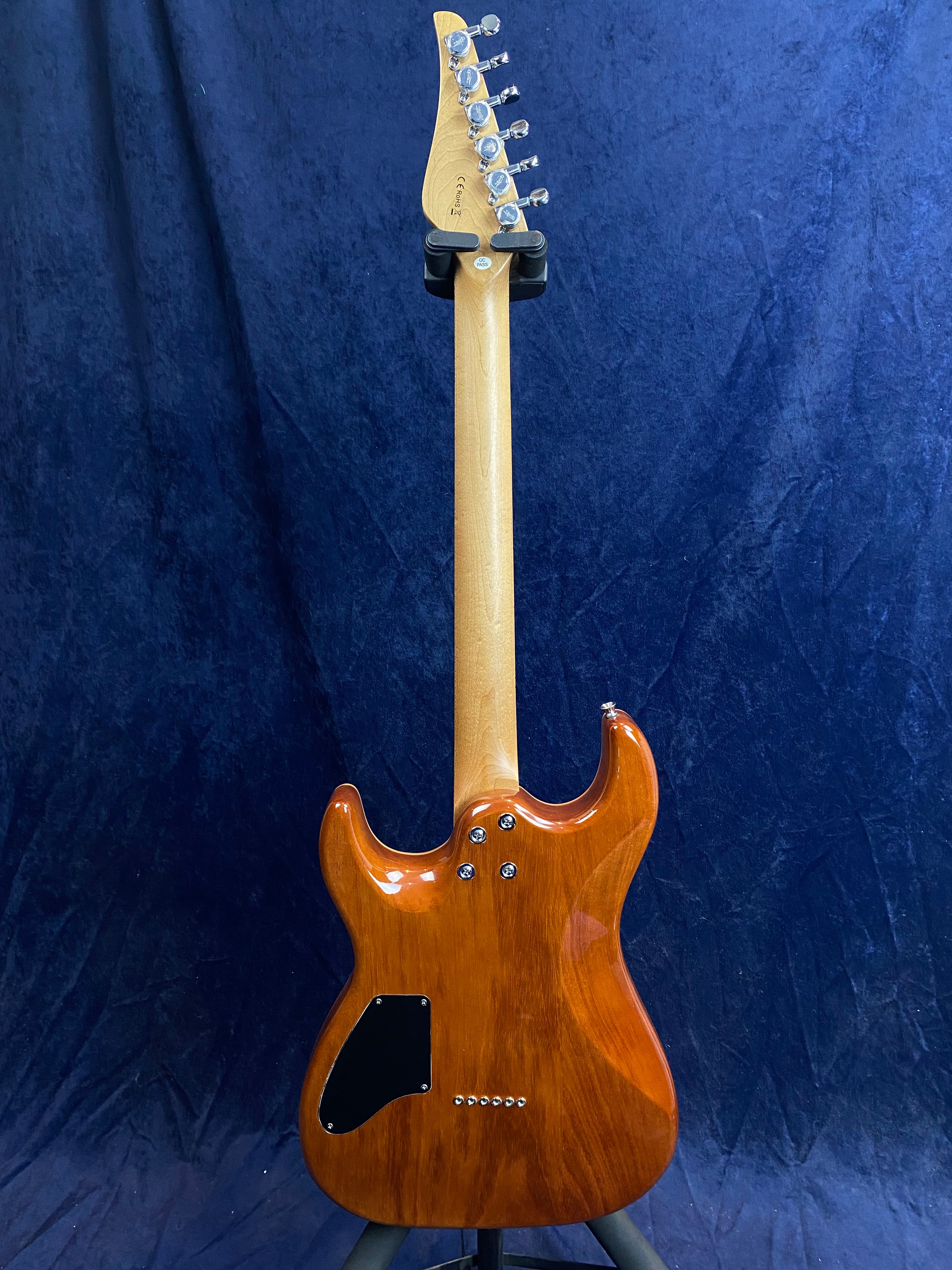 Glossy brown electric guitar shown from the back, with a natural wood neck, chrome tuning pegs, and a black plastic back plate.