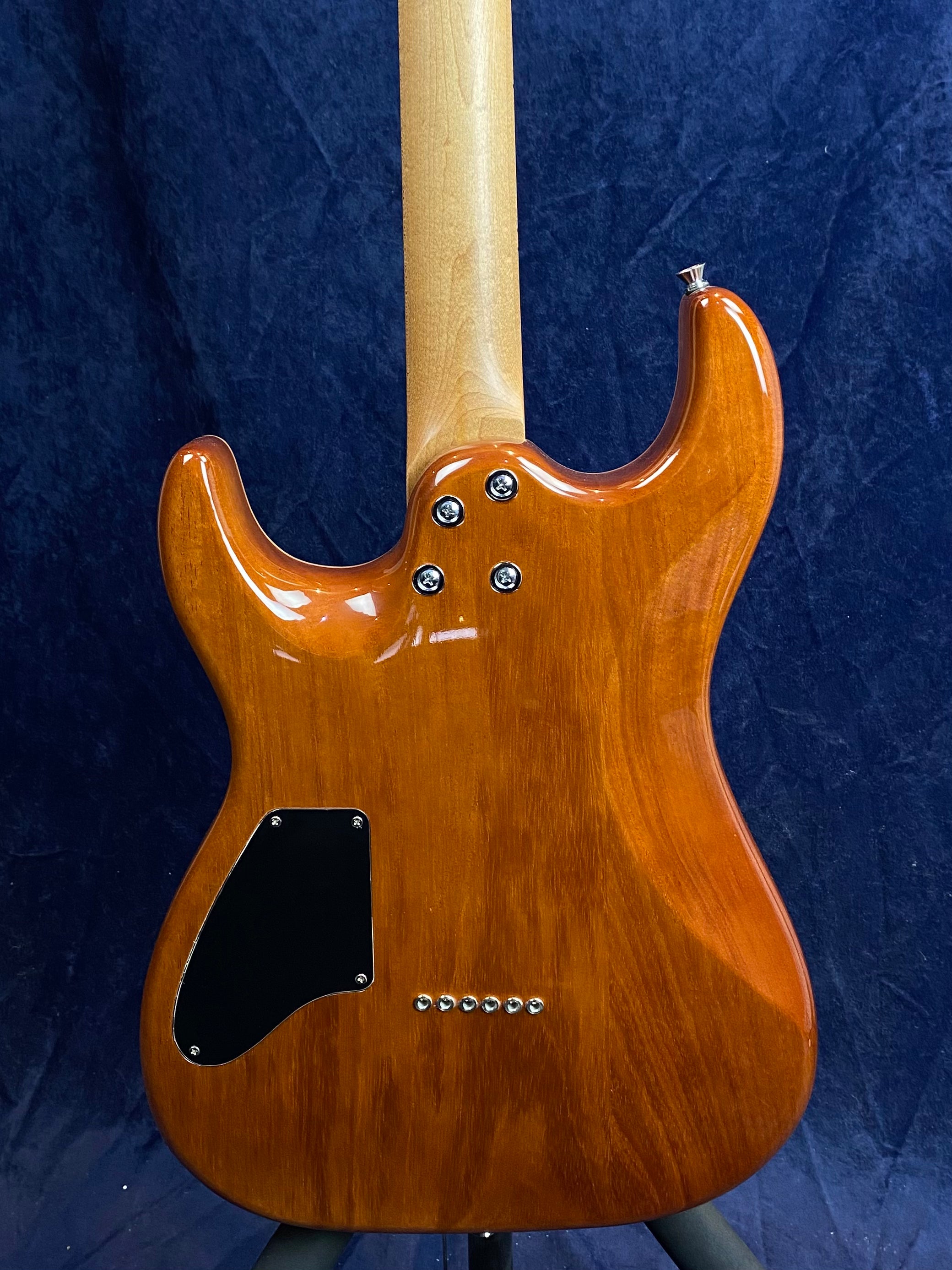 Glossy brown electric guitar back, light wood neck, black electronics cover, six string ferrules, four neck bolts.
