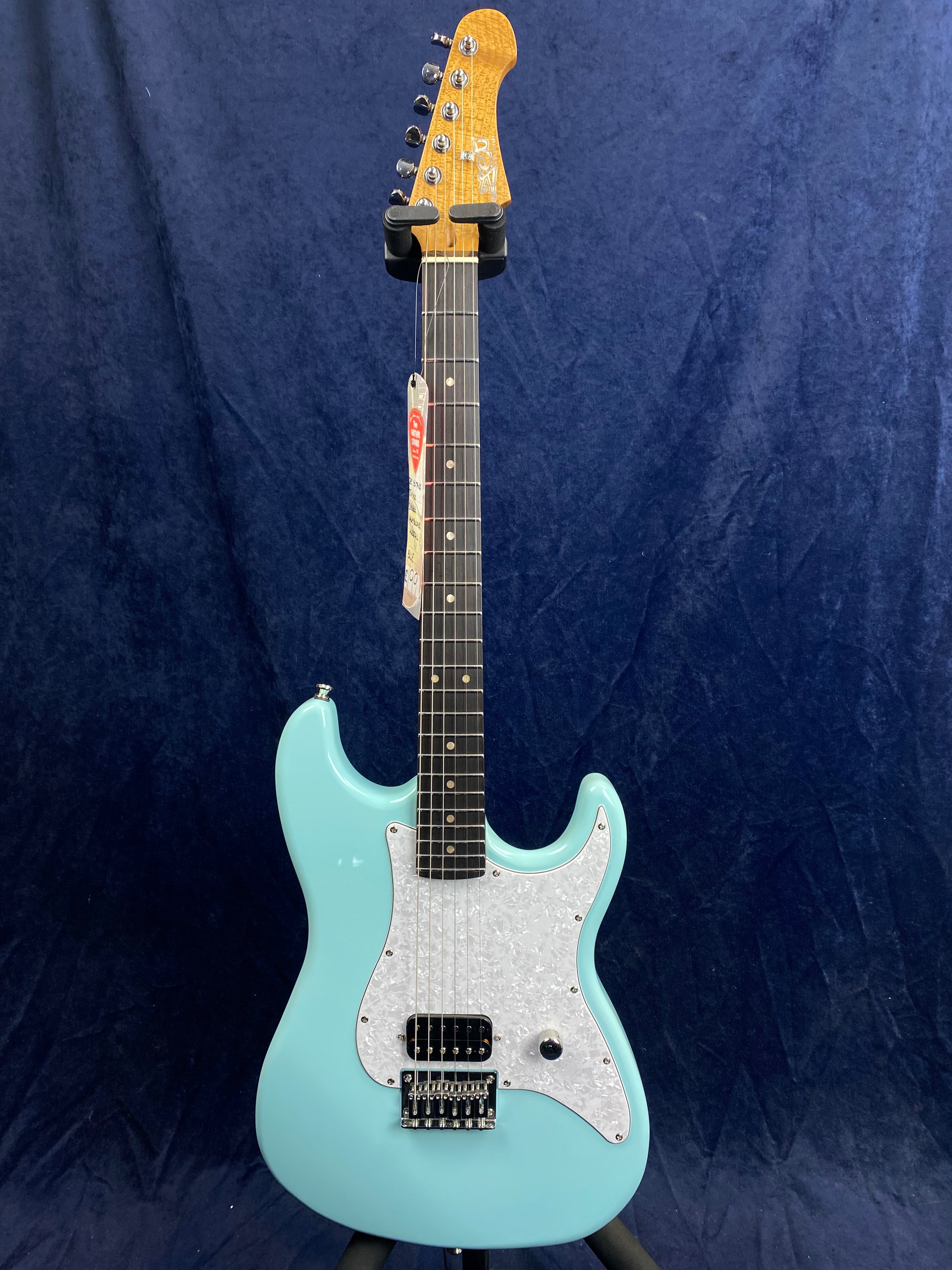 Light blue electric guitar with a white pearloid pickguard, single black bridge pickup, maple headstock, and dark fretboard, displayed upright.