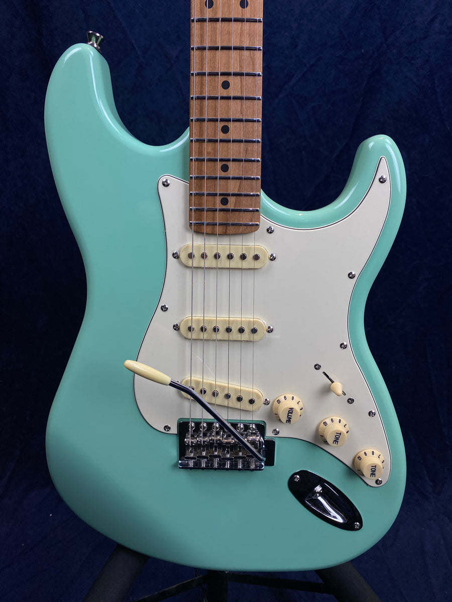 Aqua blue electric guitar with white pickguard, three cream single-coil pickups, three control knobs, and a chrome tremolo bridge.