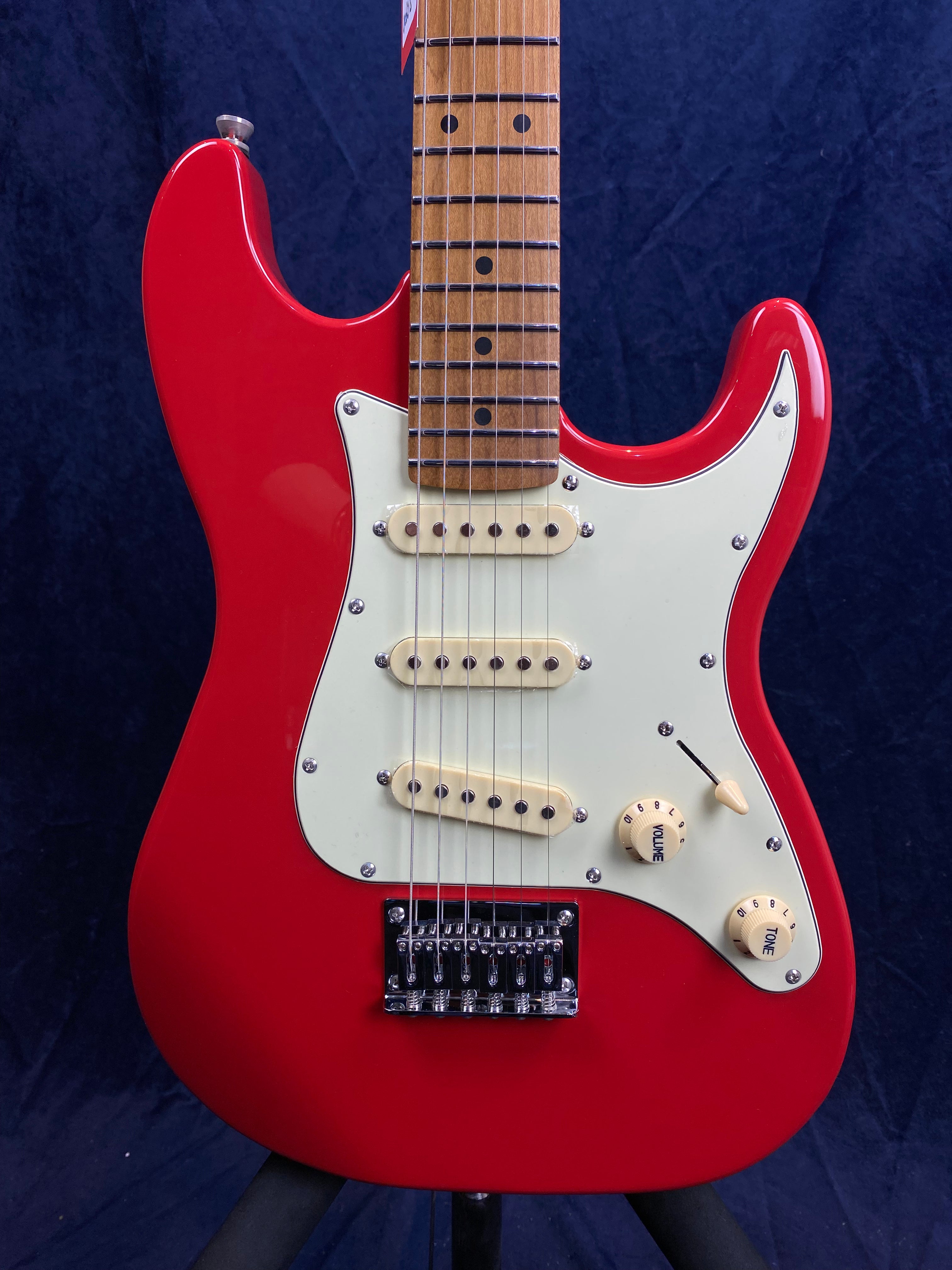 Red Jet Guitars electric guitar with a white pickguard, three single-coil pickups, and two cream control knobs against a dark background.