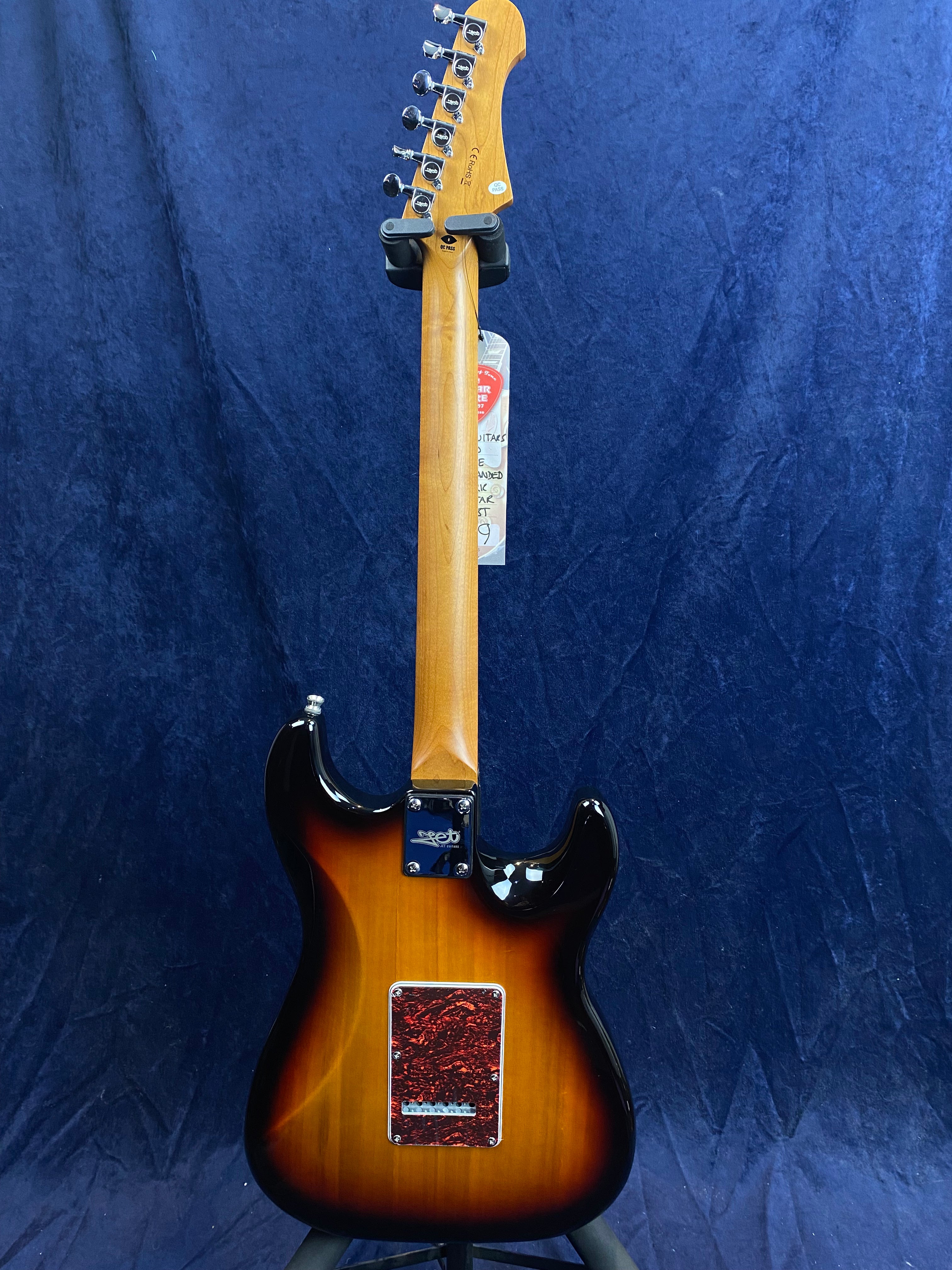 Sunburst finish electric guitar shown from the back, featuring a maple neck and a red marbled cover plate on the body.