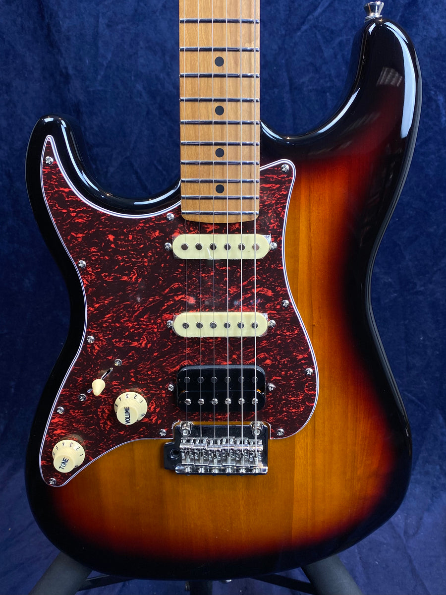 Sunburst electric guitar with a brown neck, red marbled pickguard, two cream single-coil pickups, one black humbucker, and three cream control knobs.