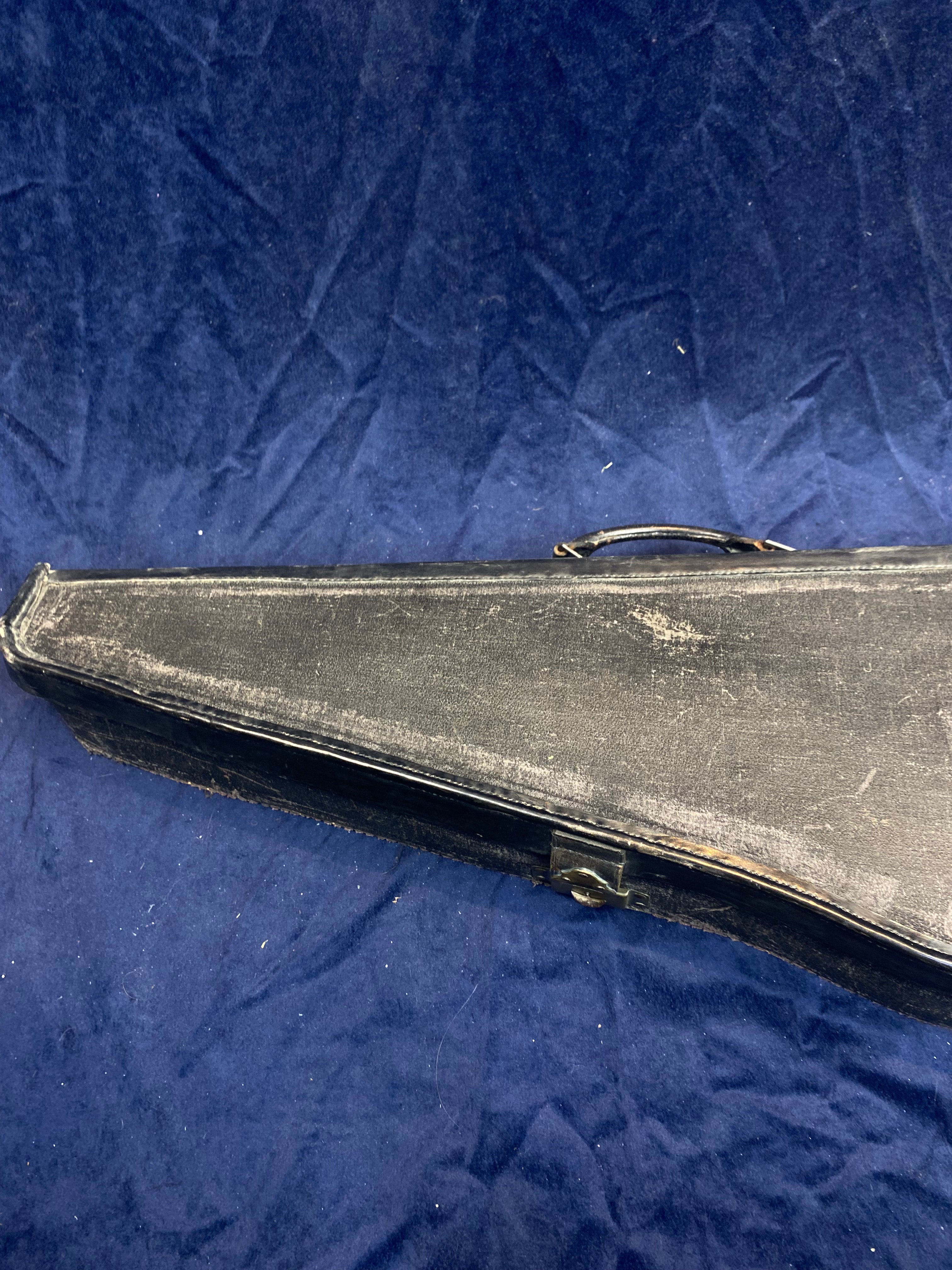 Worn black rectangular mandolin case with a handle, resting on a dark blue textured surface.