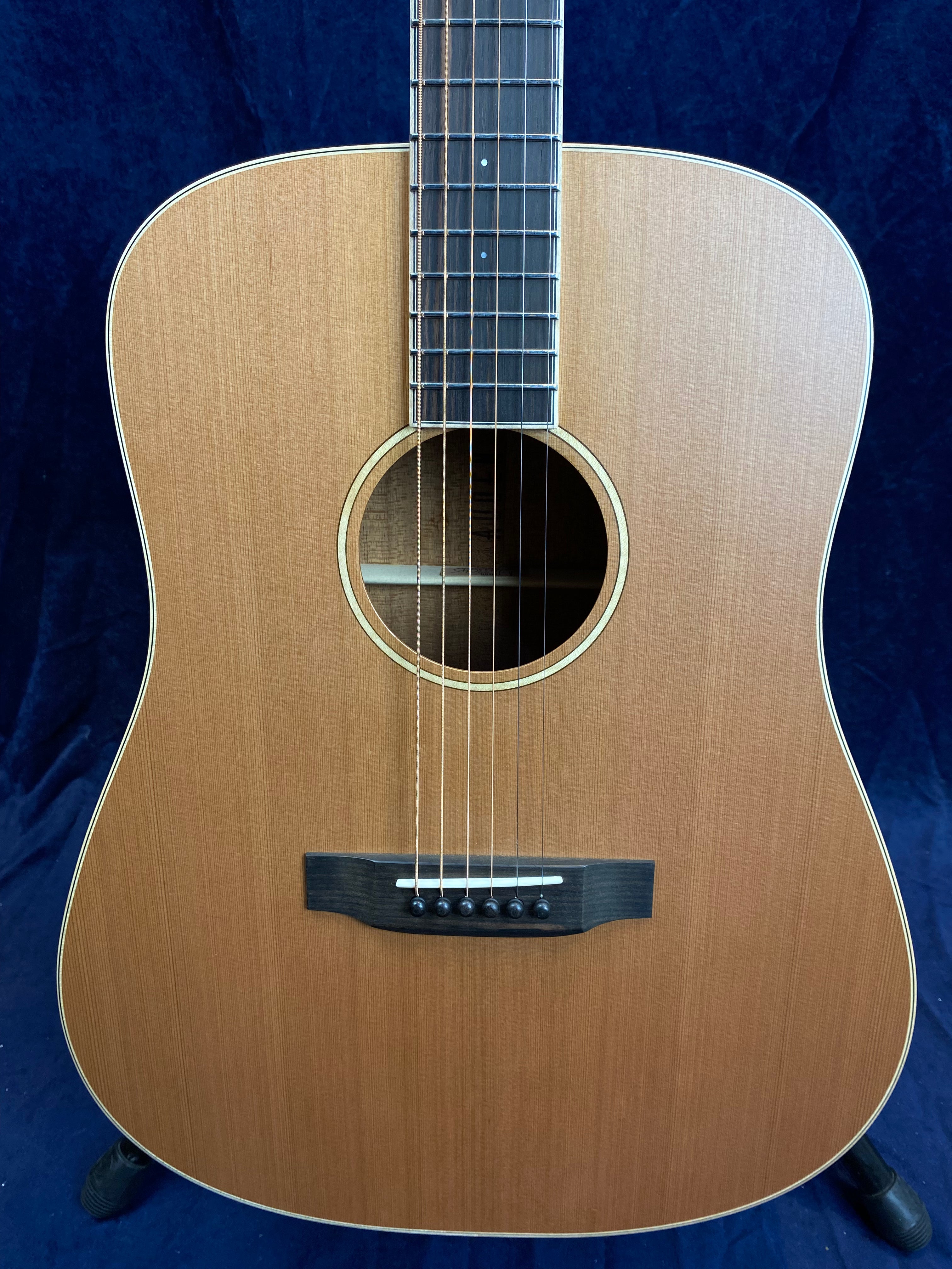 Dreadnought acoustic guitar with a natural wood finish, six steel strings, light wood top, dark bridge, and dot inlays on the fretboard.
