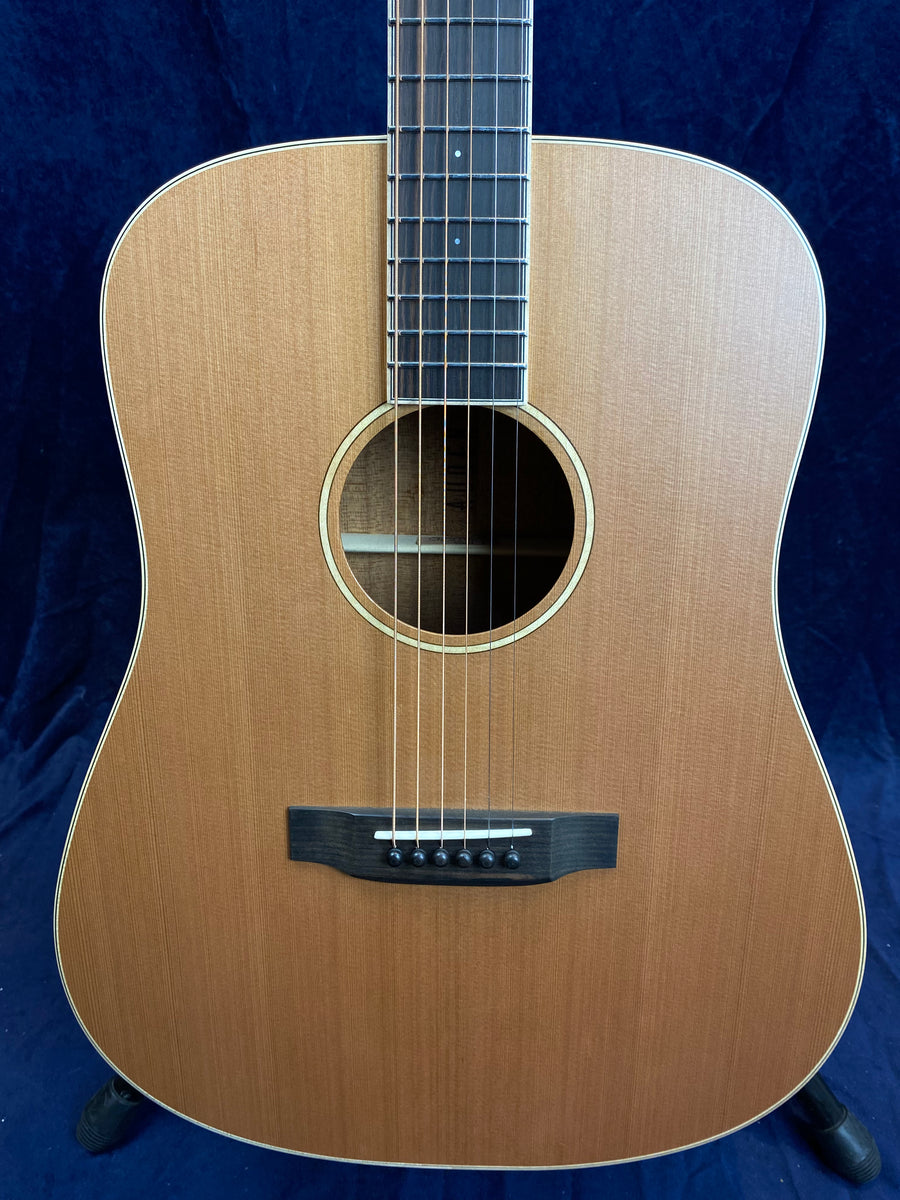 Dreadnought acoustic guitar with a natural wood finish, six steel strings, light wood top, dark bridge, and dot inlays on the fretboard.
