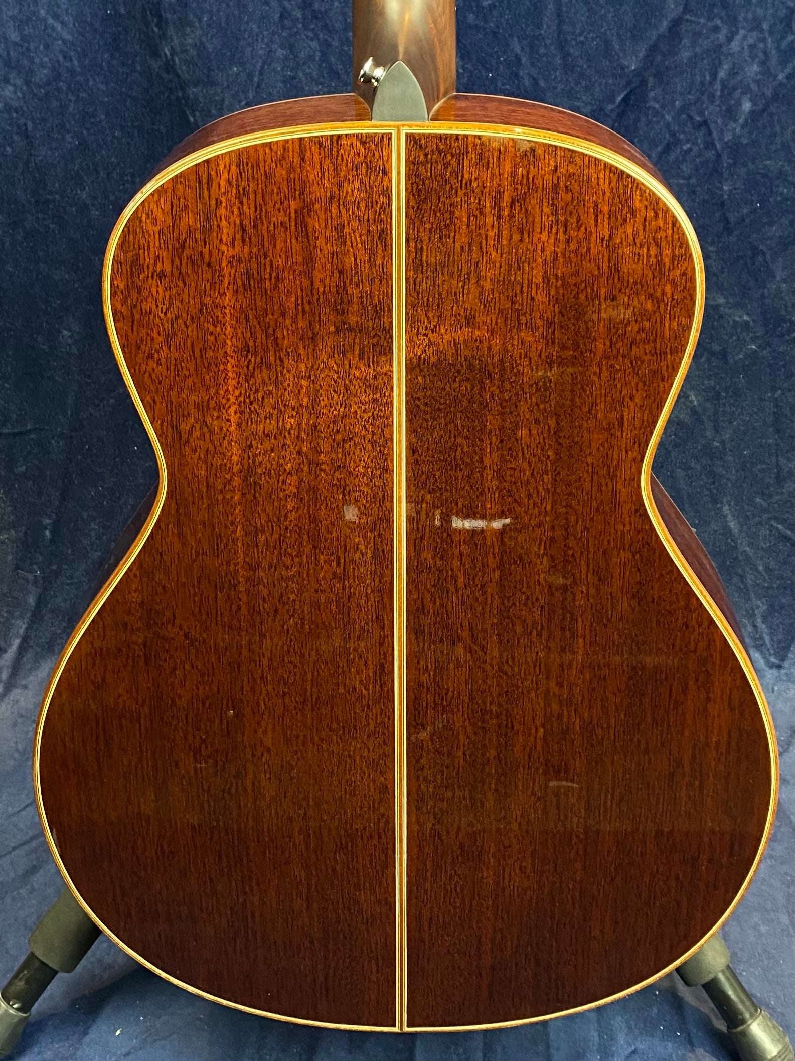 Rich brown acoustic guitar back with a glossy wood finish, divided by a thin vertical strip and bordered by light-colored edging.