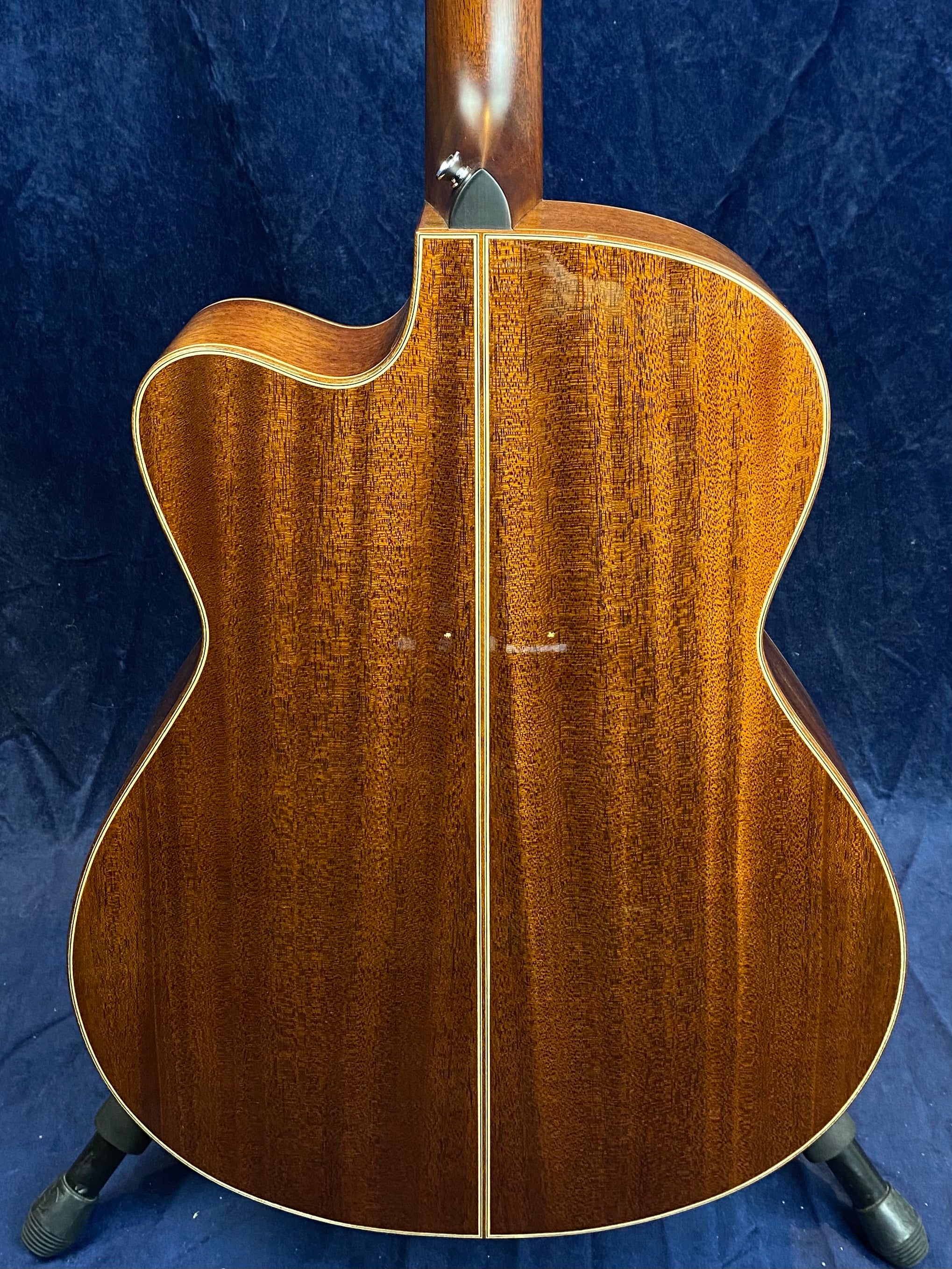 Glossy mahogany acoustic guitar back with a center seam, cream binding, and a cutaway for easier access to higher frets.