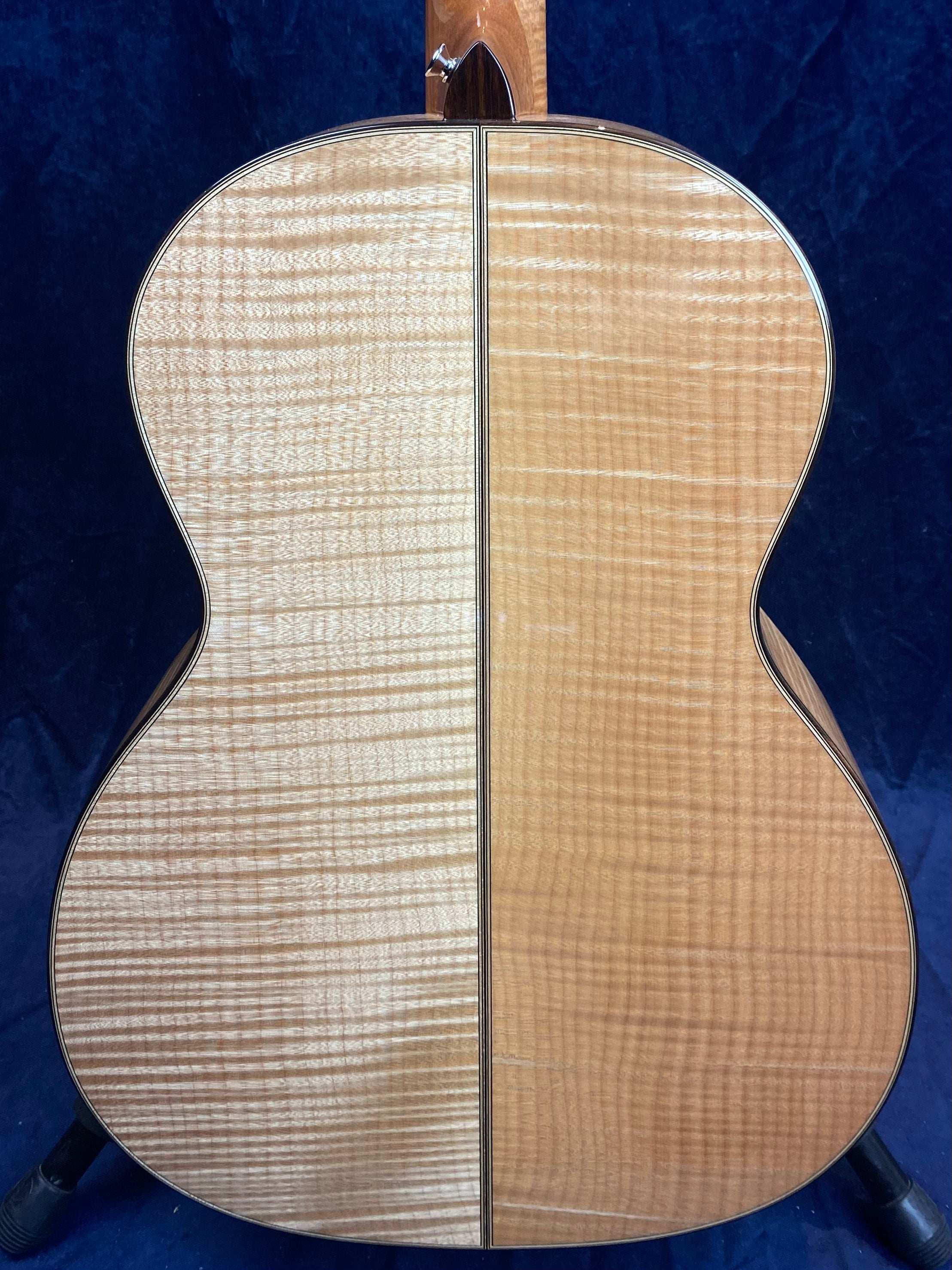 Back of an acoustic guitar with two-tone flamed wood, divided vertically down the center, showing contrasting light and medium finishes.