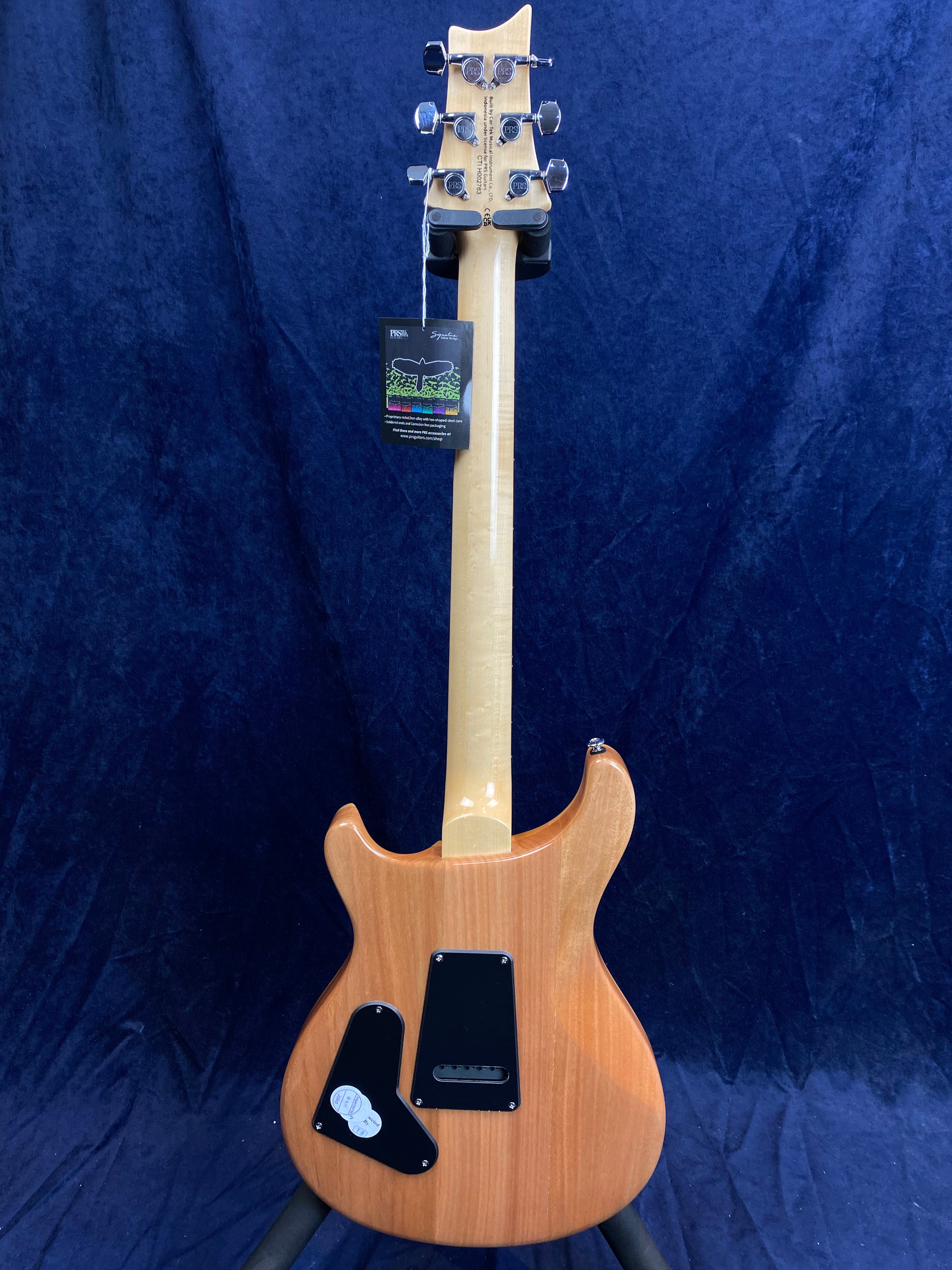 Natural wood finish electric guitar shown from the back, with a maple neck, six tuning pegs, and two black control cavity covers on the body.