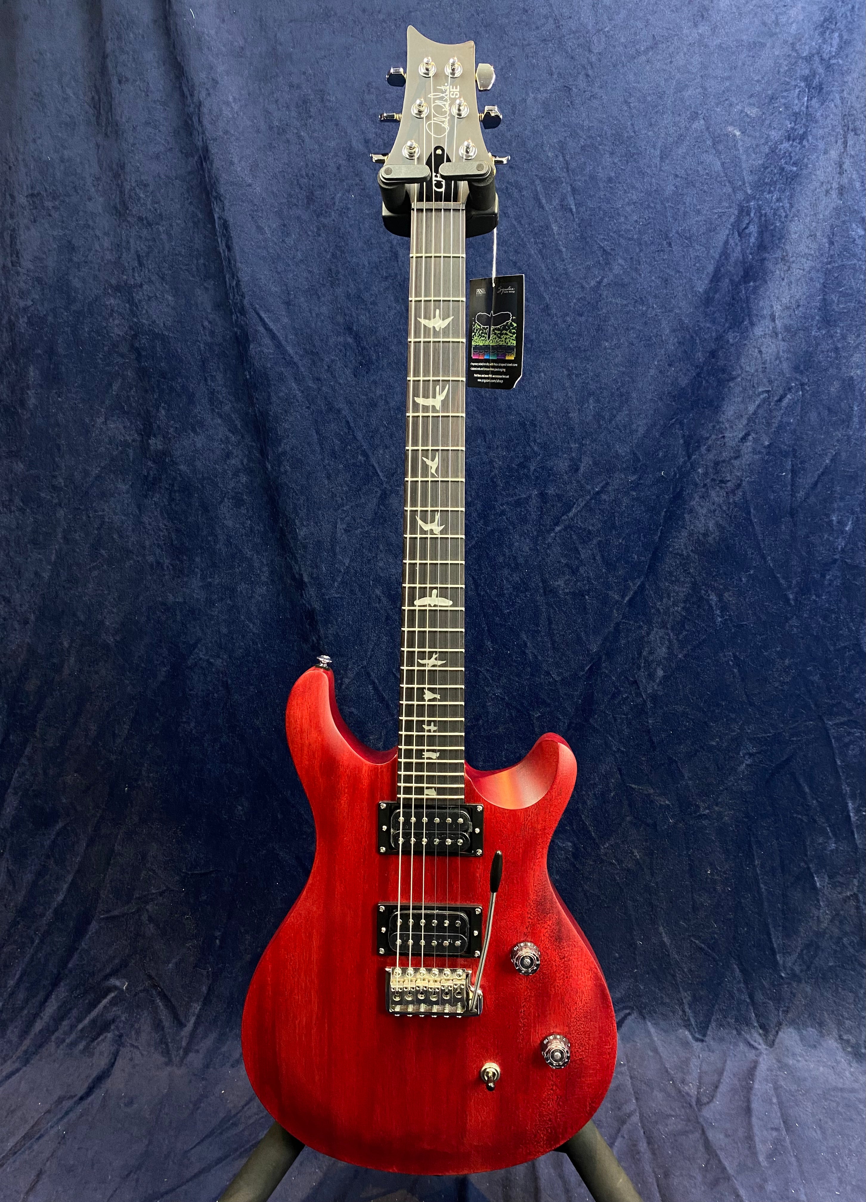 Red electric guitar with double cutaway body, two humbucker pickups, tremolo bridge, and fretboard inlays shaped like birds.