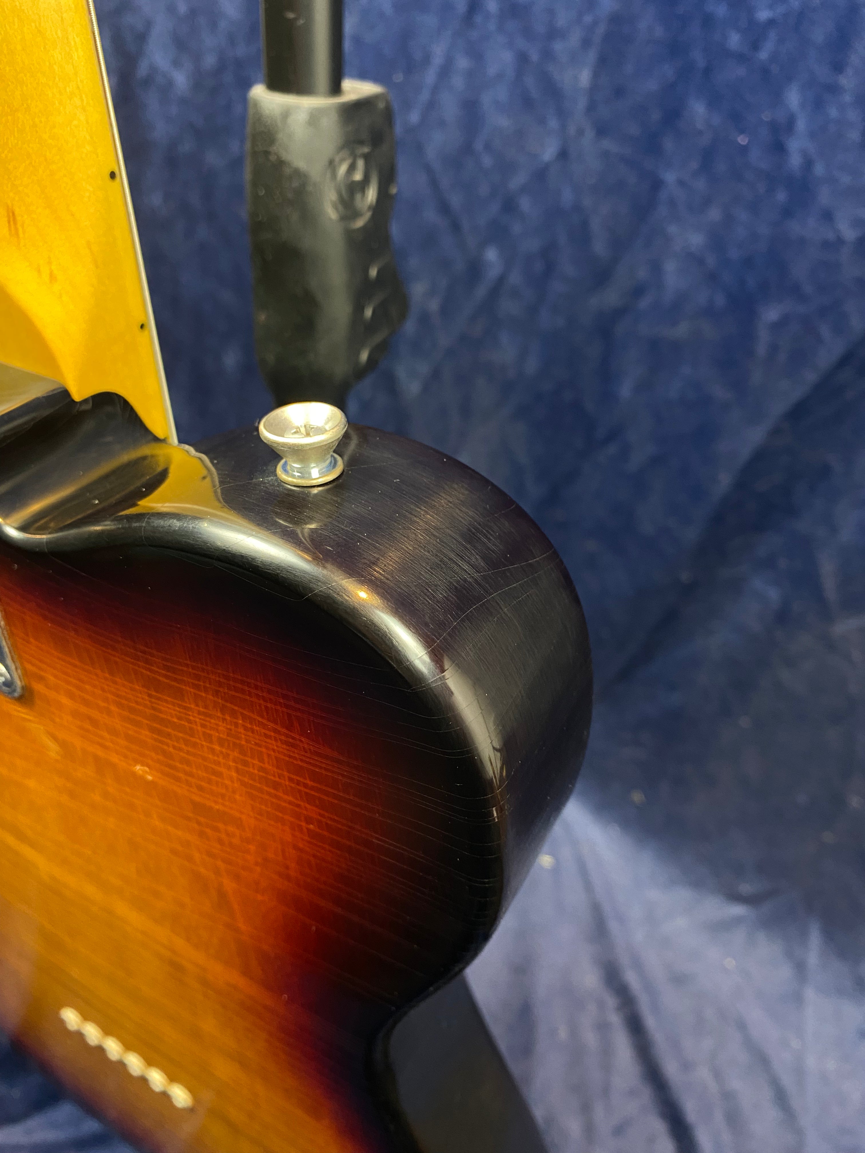 Electric guitar body in sunburst finish with visible fine cracks in the lacquer, strap button on the upper horn, and part of the neck joint shown.