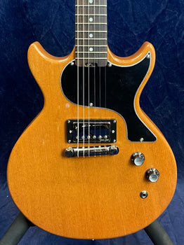 Natural wood finish electric guitar with double cutaway body, single black pickup, three control knobs, and a large black pickguard.