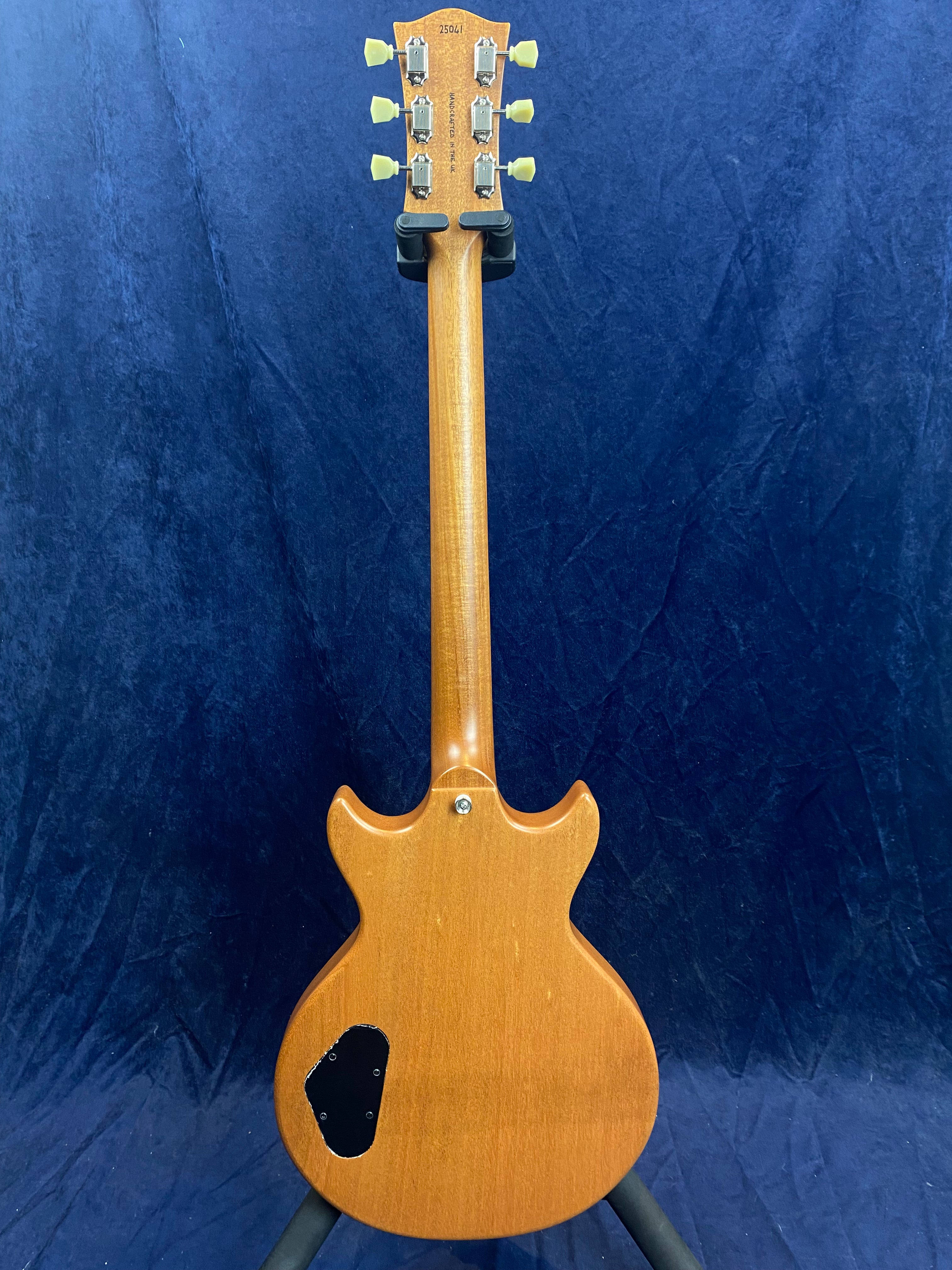 Mahogany-finished electric guitar shown from the back, with six tuning pegs, a double-cutaway body, and a black plastic electronics cover on the lower left.