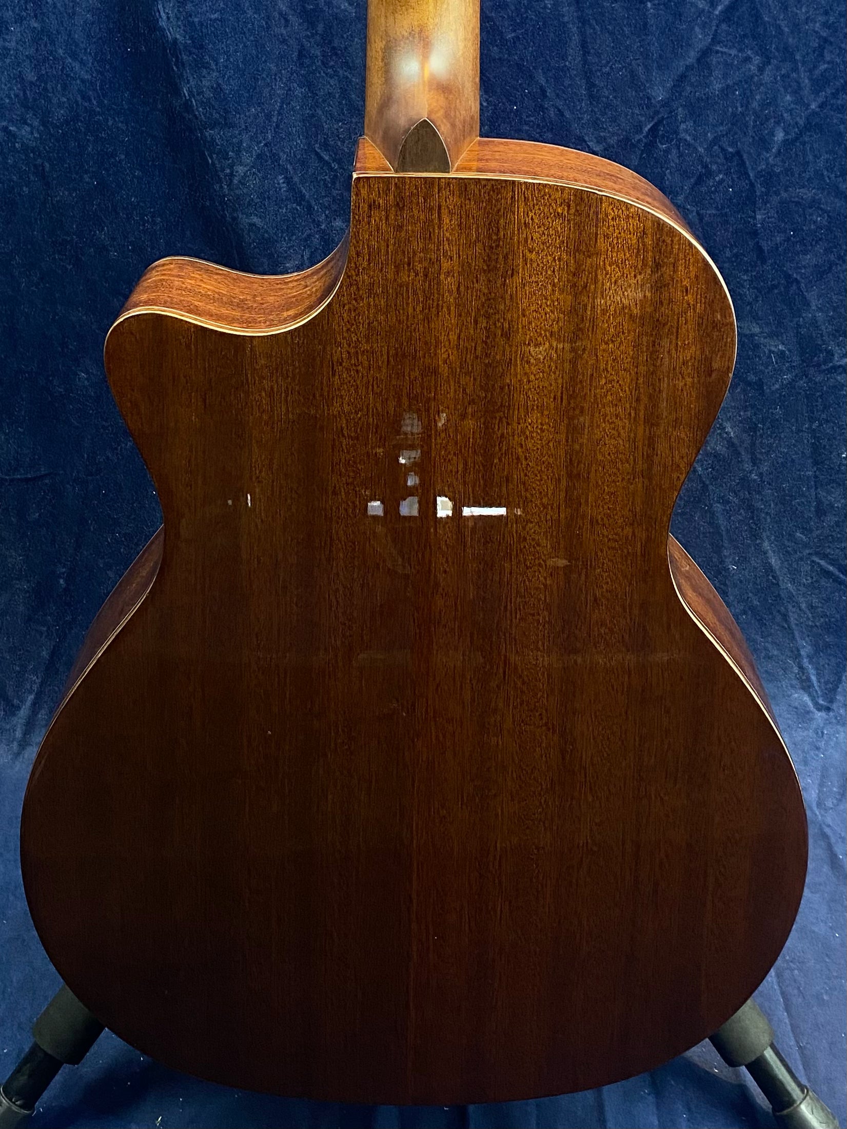 Back of an acoustic guitar made of dark brown wood with some visible scratches and scuffs near the center.