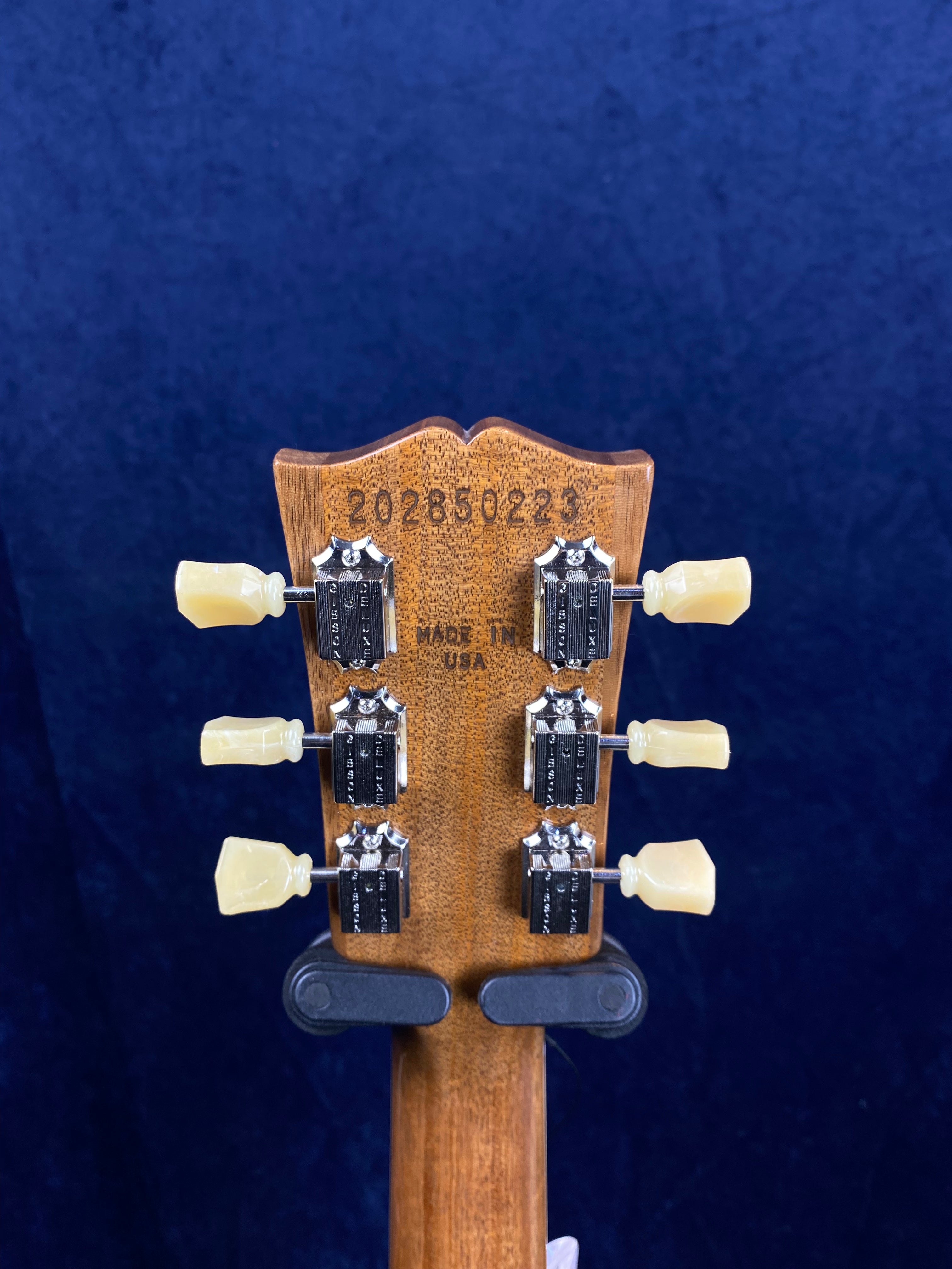 Back of an electric guitar headstock showing six tuning pegs, serial number 202850223, and “Made in USA” stamped on the wood.