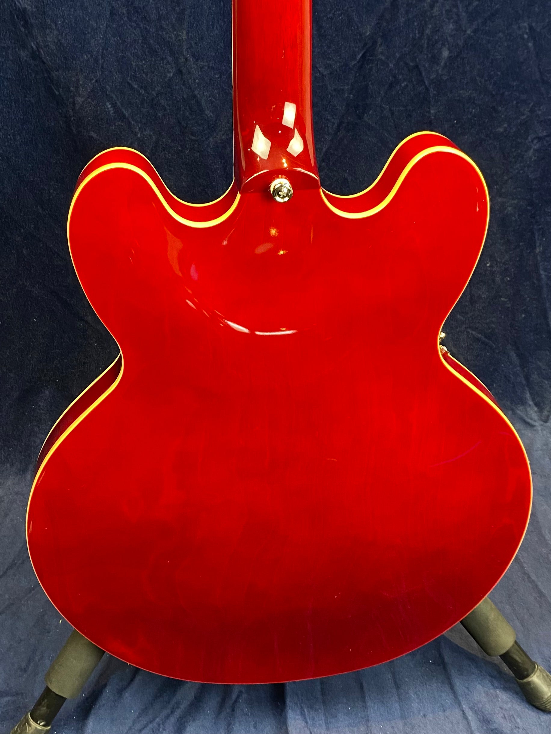 Electric guitar with a glossy cherry red back, double cutaway shape, and cream binding outlining the body and neck.