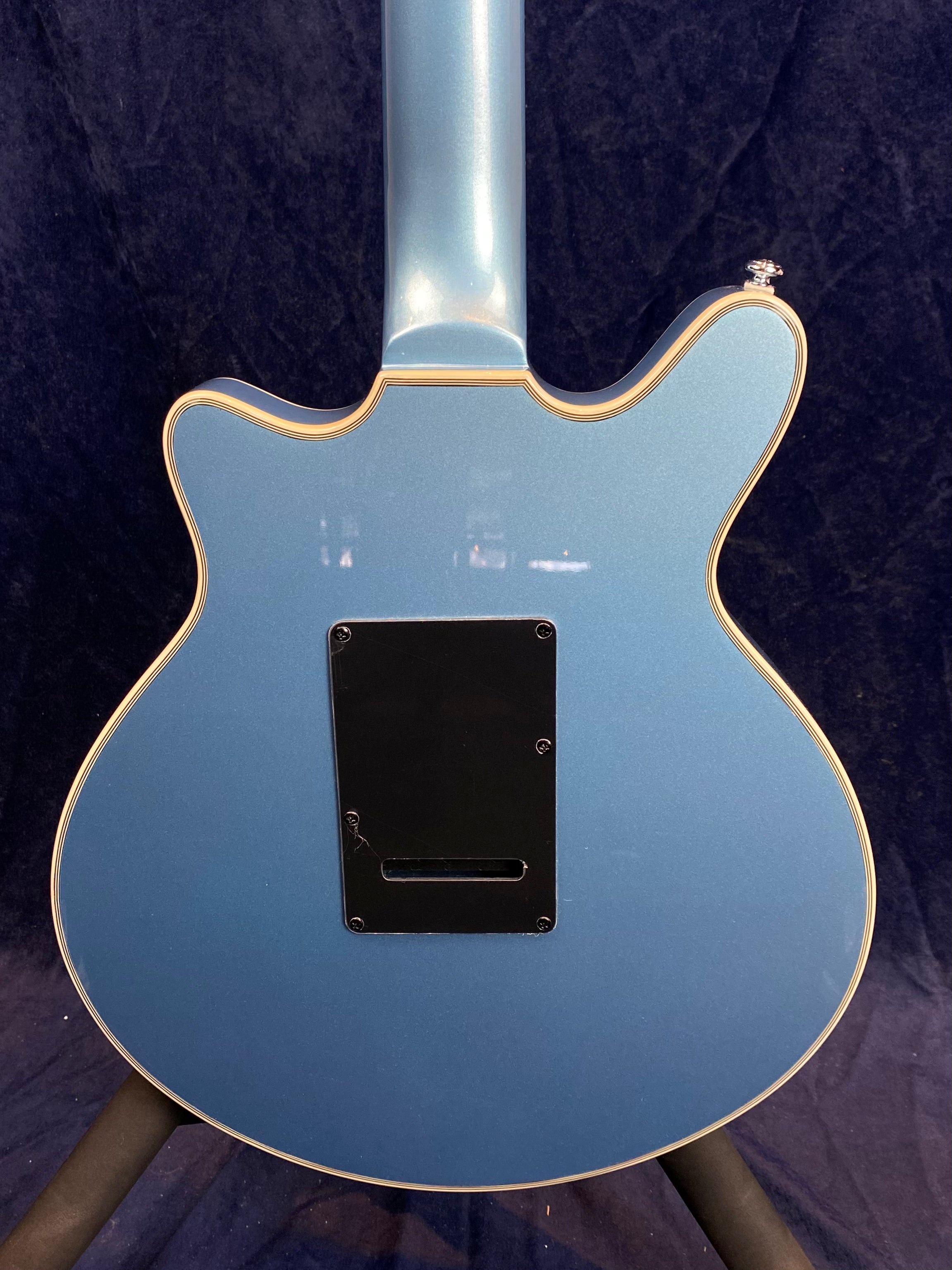 Metallic blue electric guitar, double cutaway shape, cream binding, shown from the back with a black rectangular electronics cover plate.